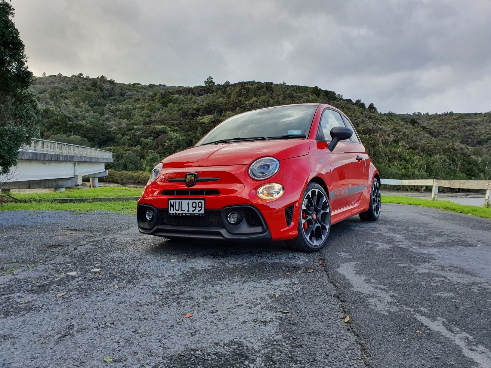 A picture of a red Abarth 595 Competizione by the water