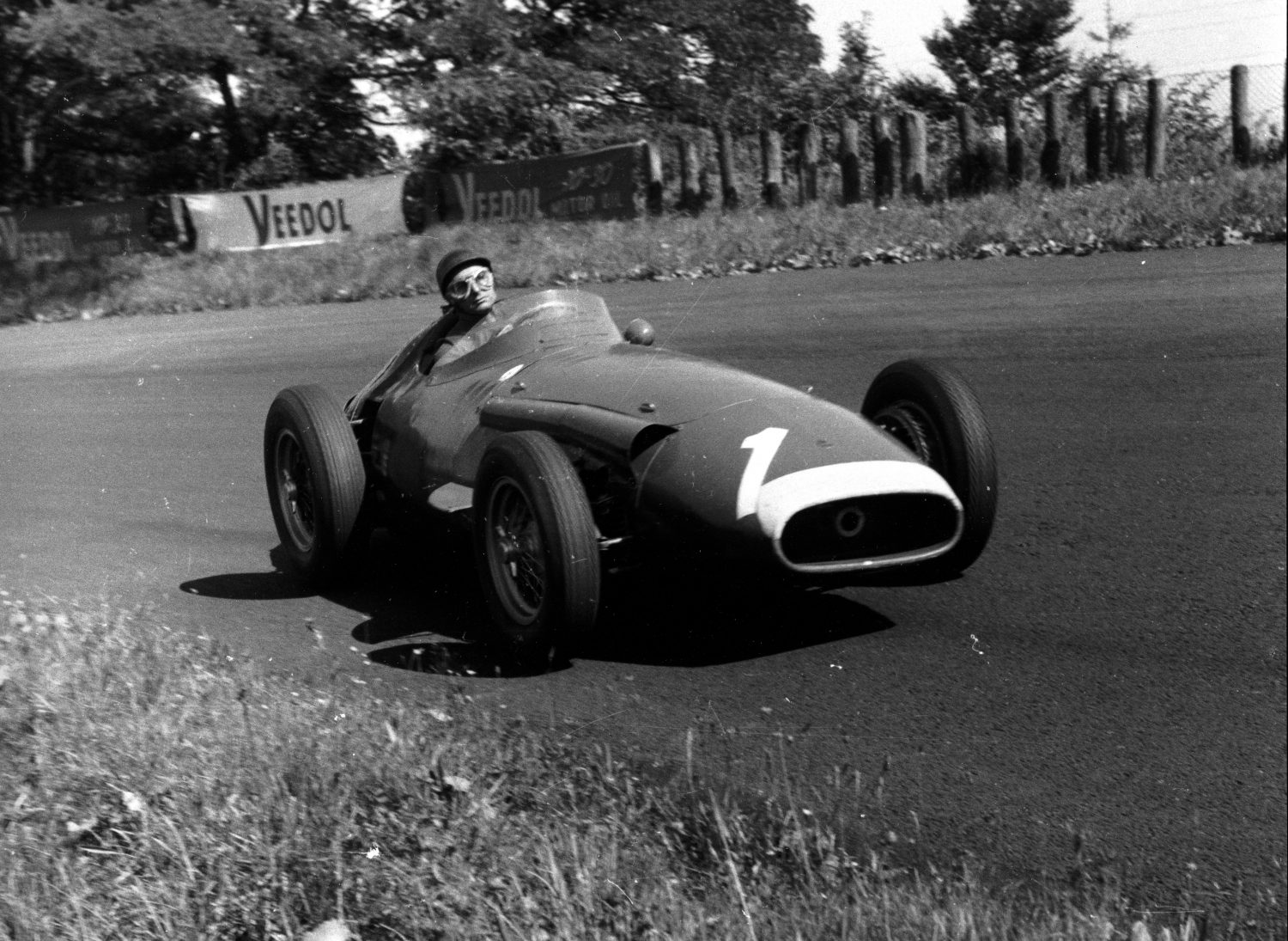Black and white photo of Juan Manuel Fangio behind the wheel of the Maserati 250F