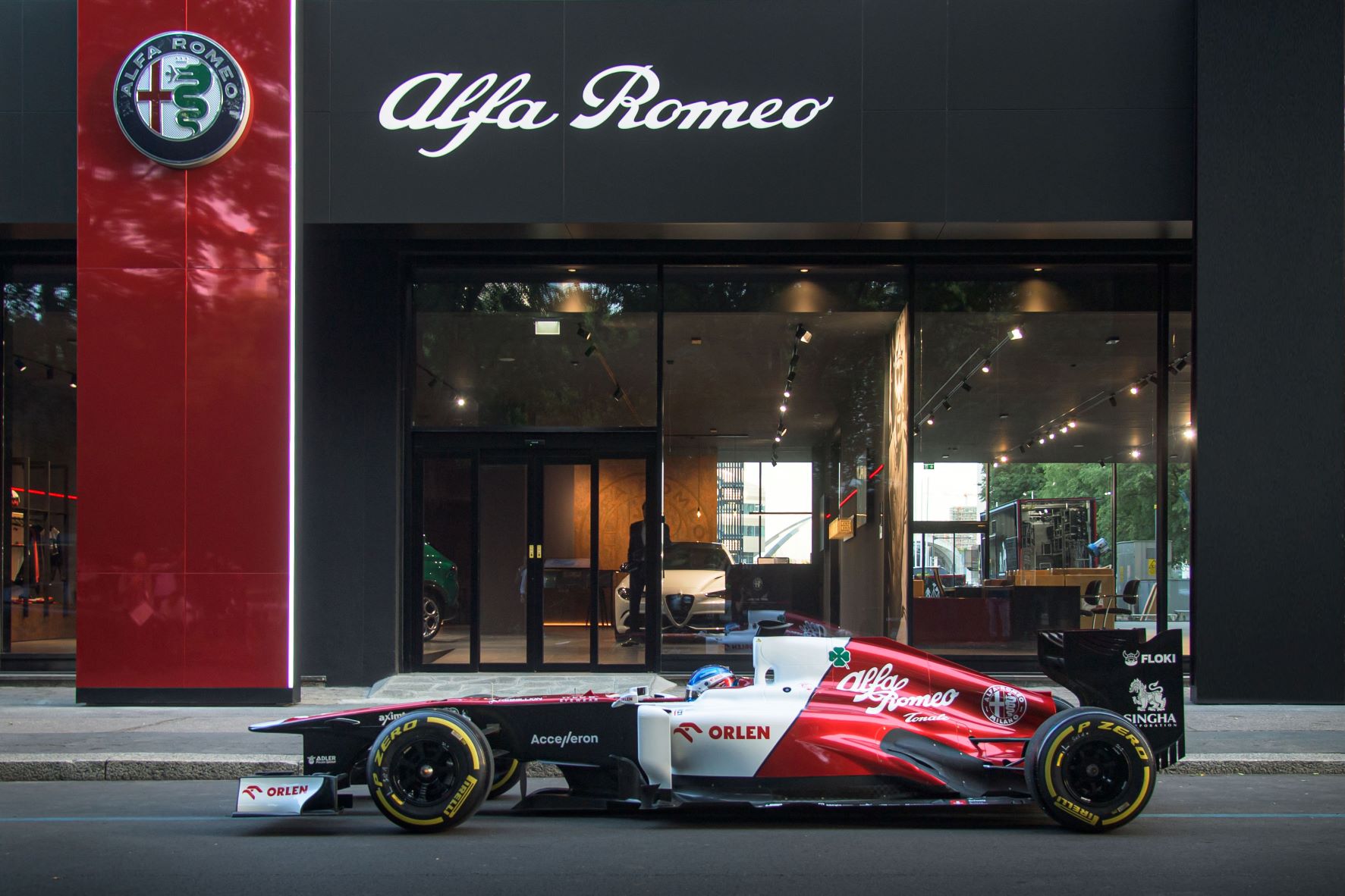 An Alfa Romeo Orlen F1 team car in front of an Alfa Romeo dealership in Milan