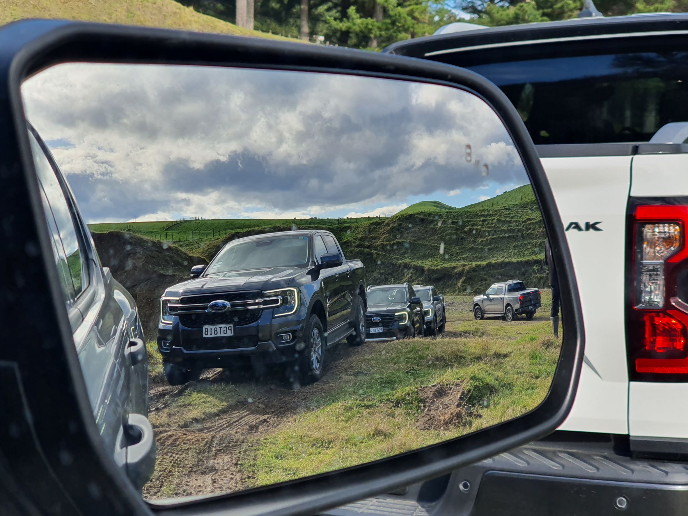 Picture of a Ford Ranger side view mirror showing a fleet of 2022 Ford Rangers going-off road in Havelock North, New Zealand