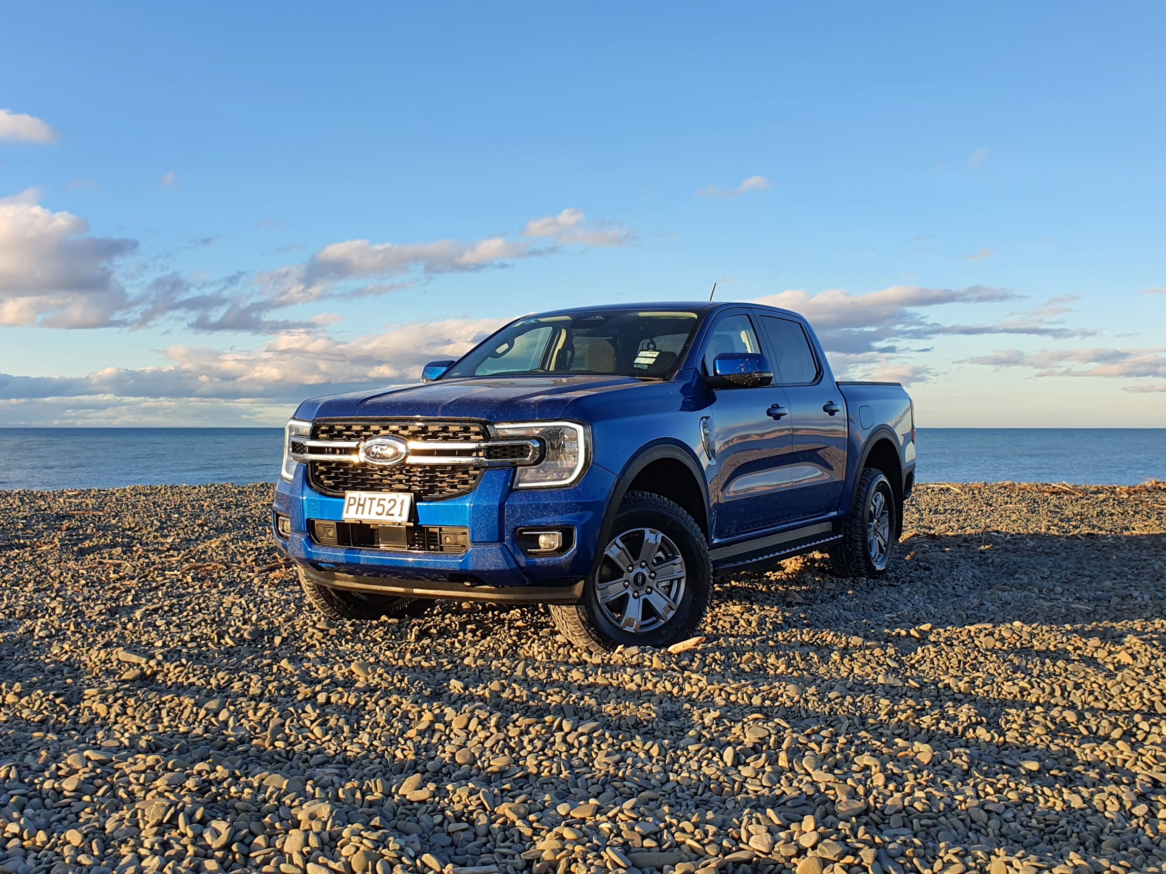Front three quarters view of a 2022 Ford Ranger bi-turbo in blue. Photographed on a beach in Havelock North, New Zealand