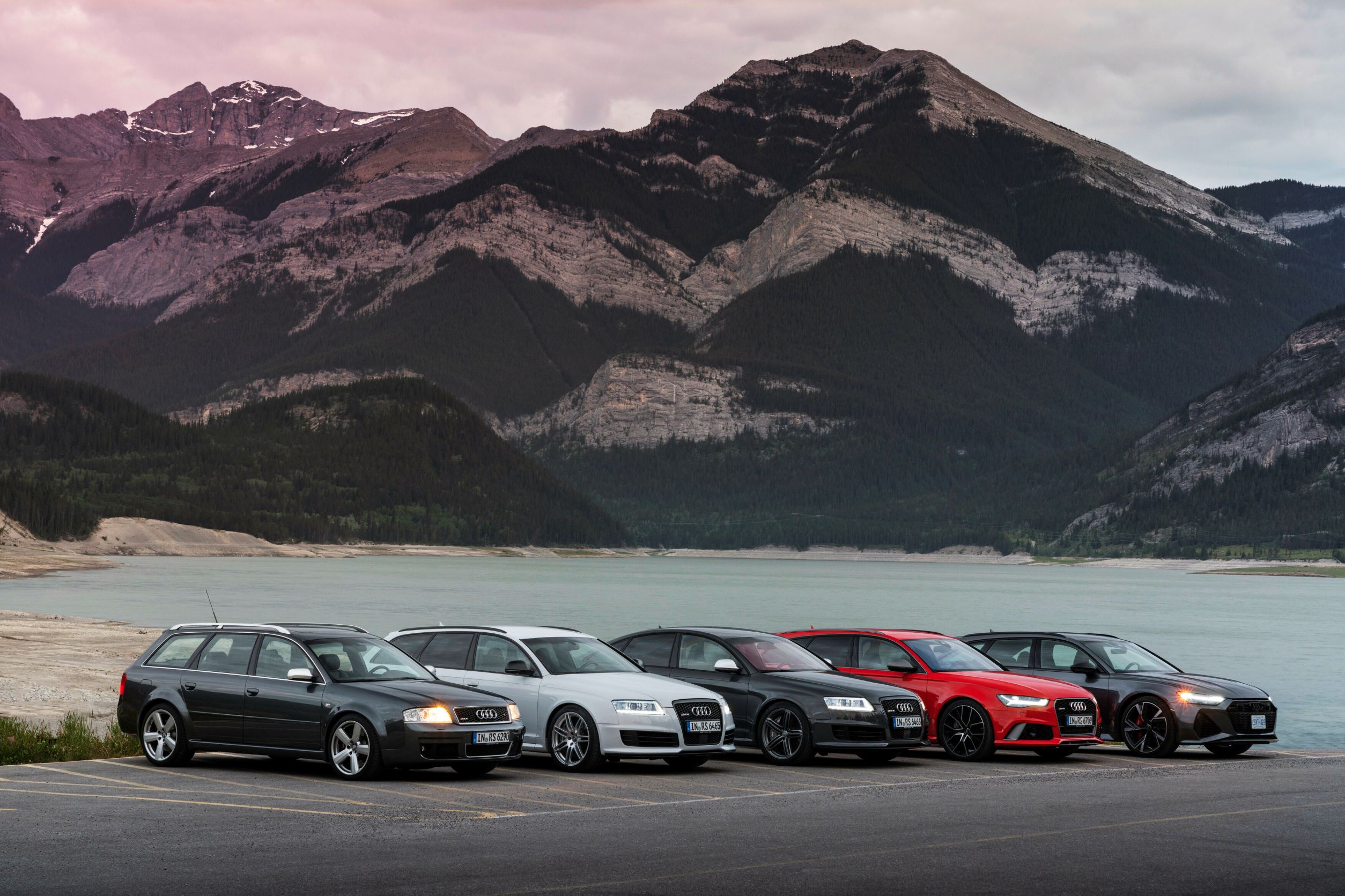Four generations of the Audi RS6 being photographed by a lake