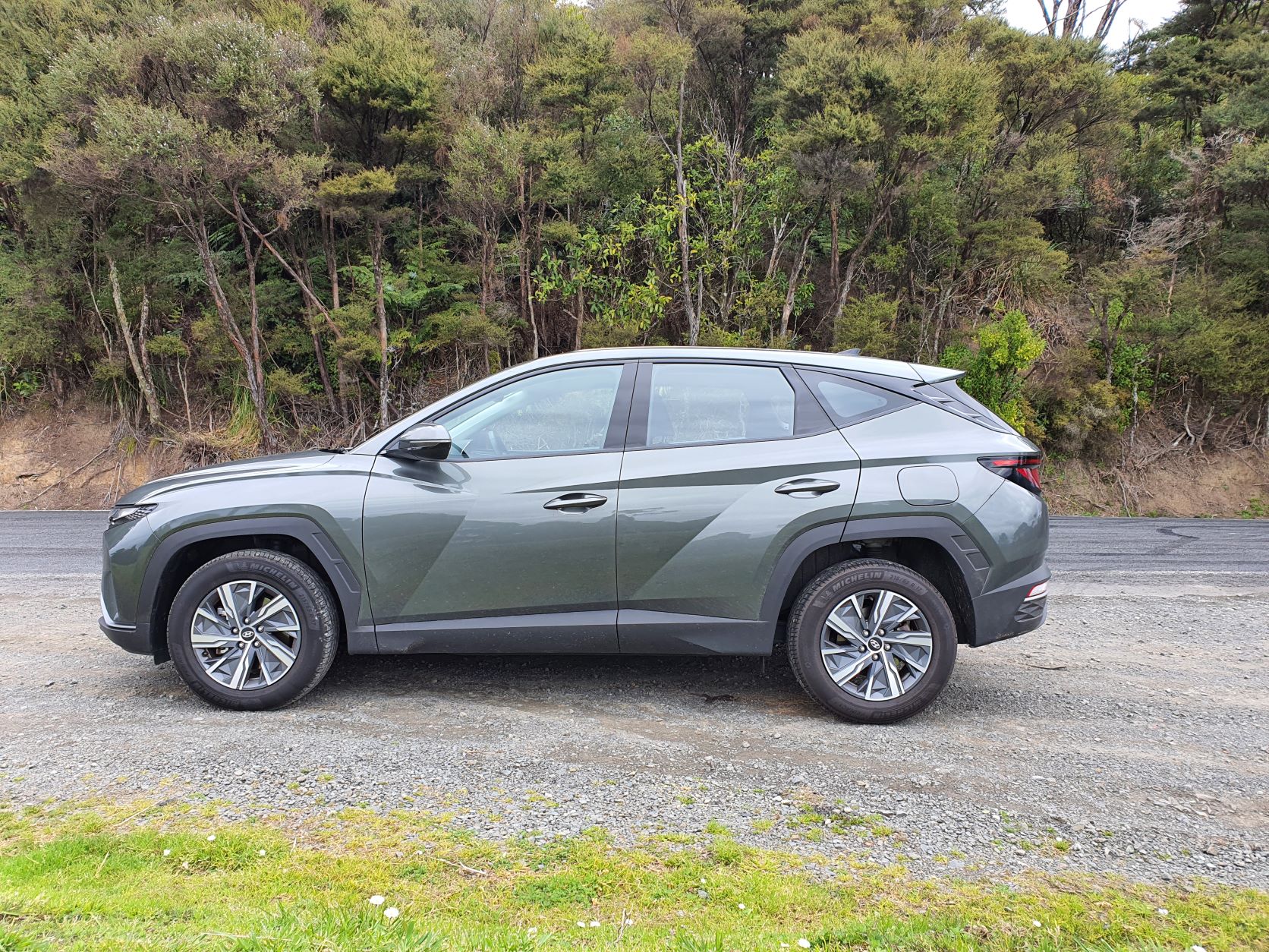 Side view of the 2022 Hyundai Tucson Hybrid in green with a backdrop of nature