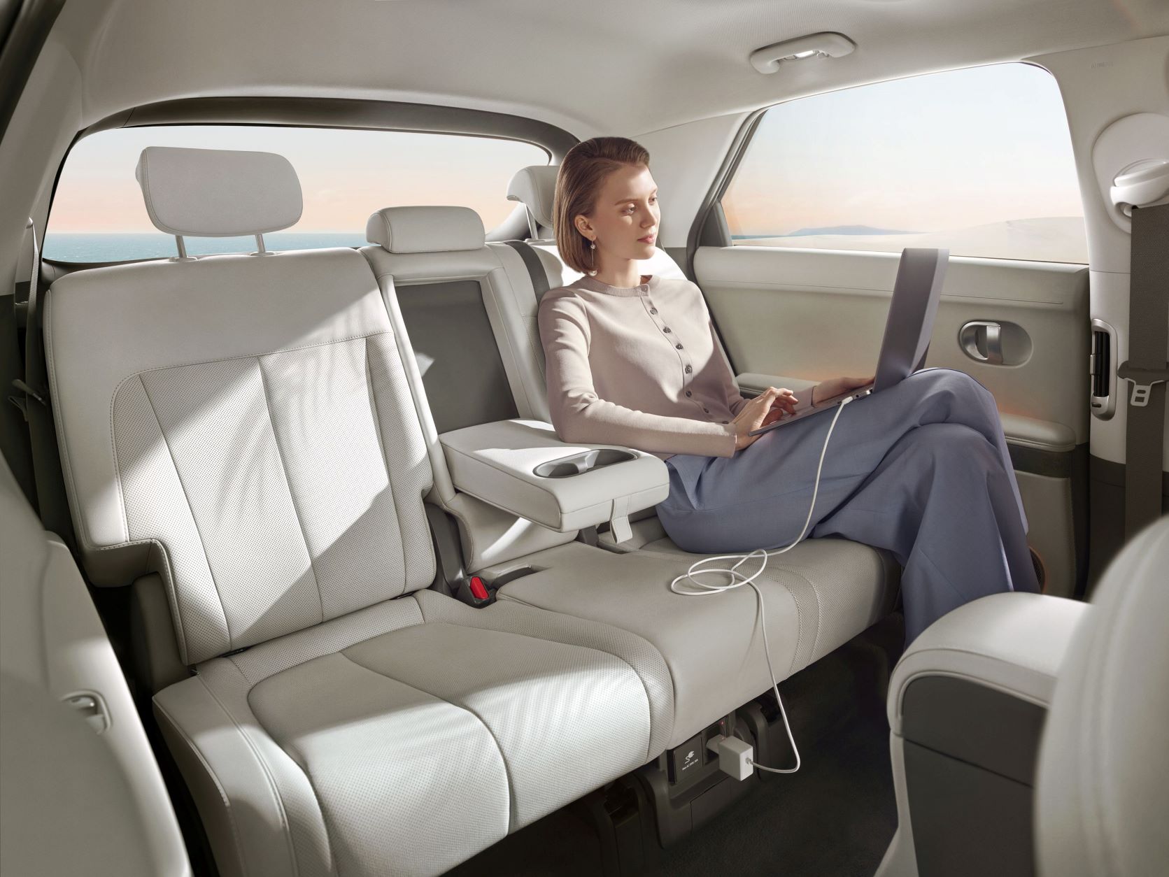 A person sitting in the rear seat of the Hyundai IONIQ 5 charging their device from the household socket