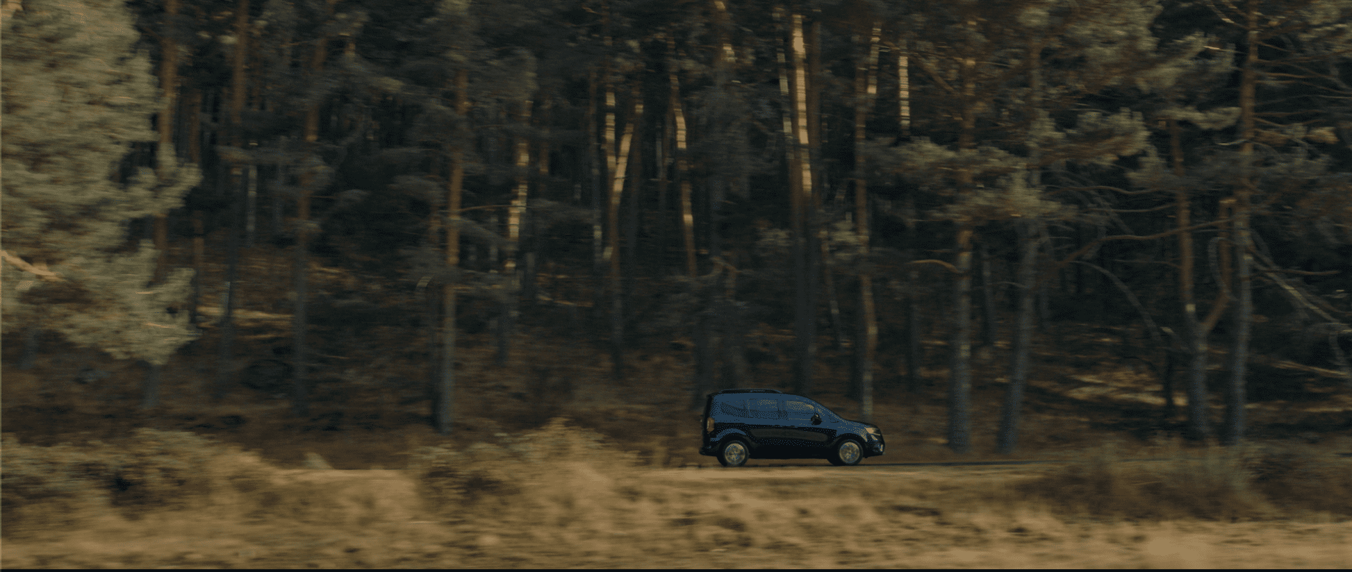 Zoomed out side view of a Renault Kangoo E-Tech in motion.