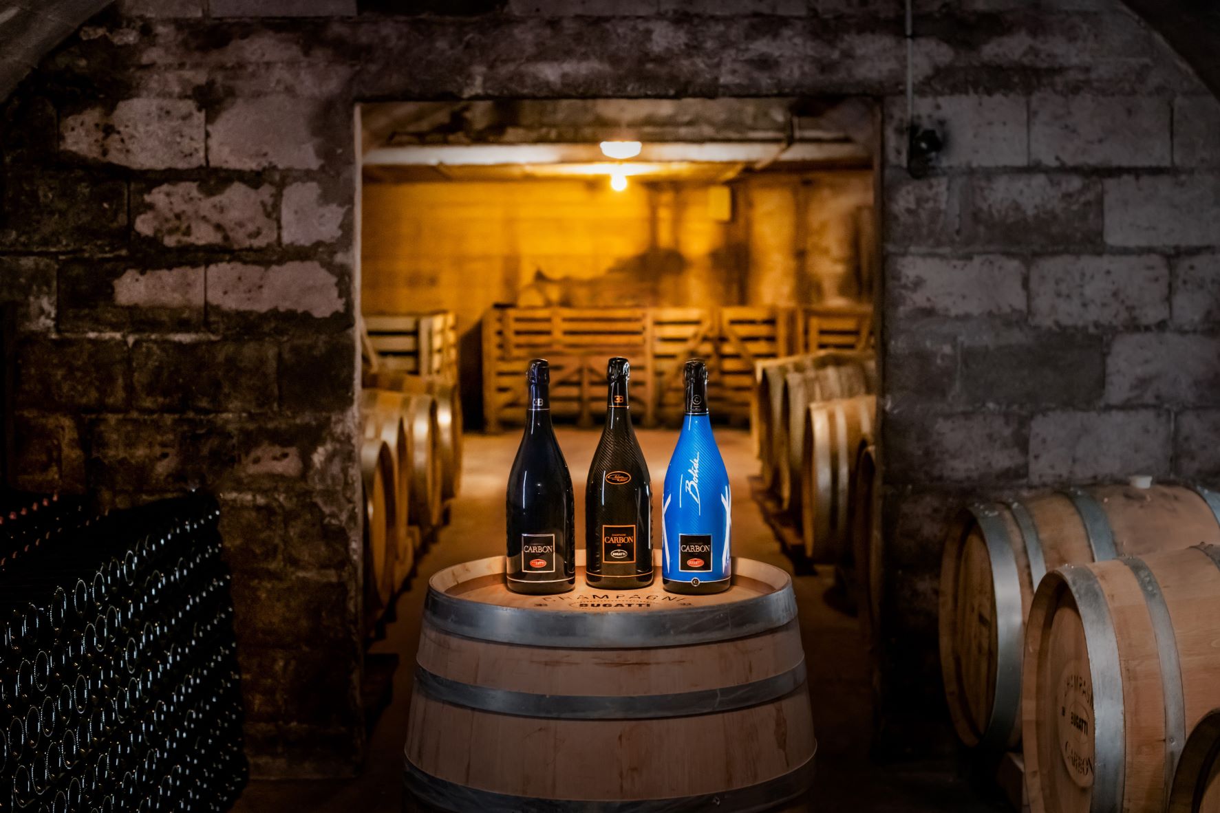 A trio of Bugatti collaborations with Champagne Carbon sitting atop a wine barrel at Champagne Carbon's winery.
