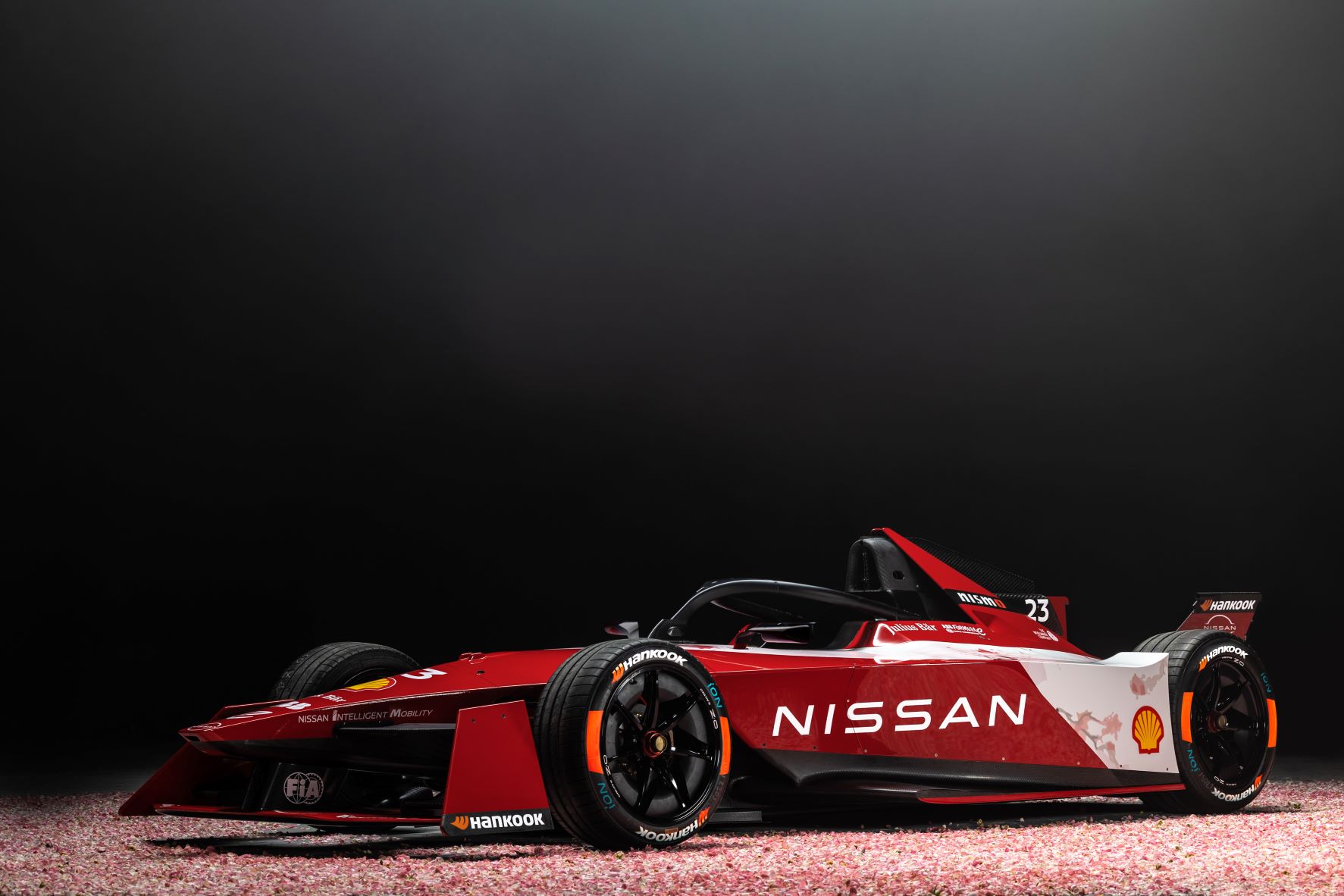 Front three quarters view of the Team Nissan Formula E race car in red and white.