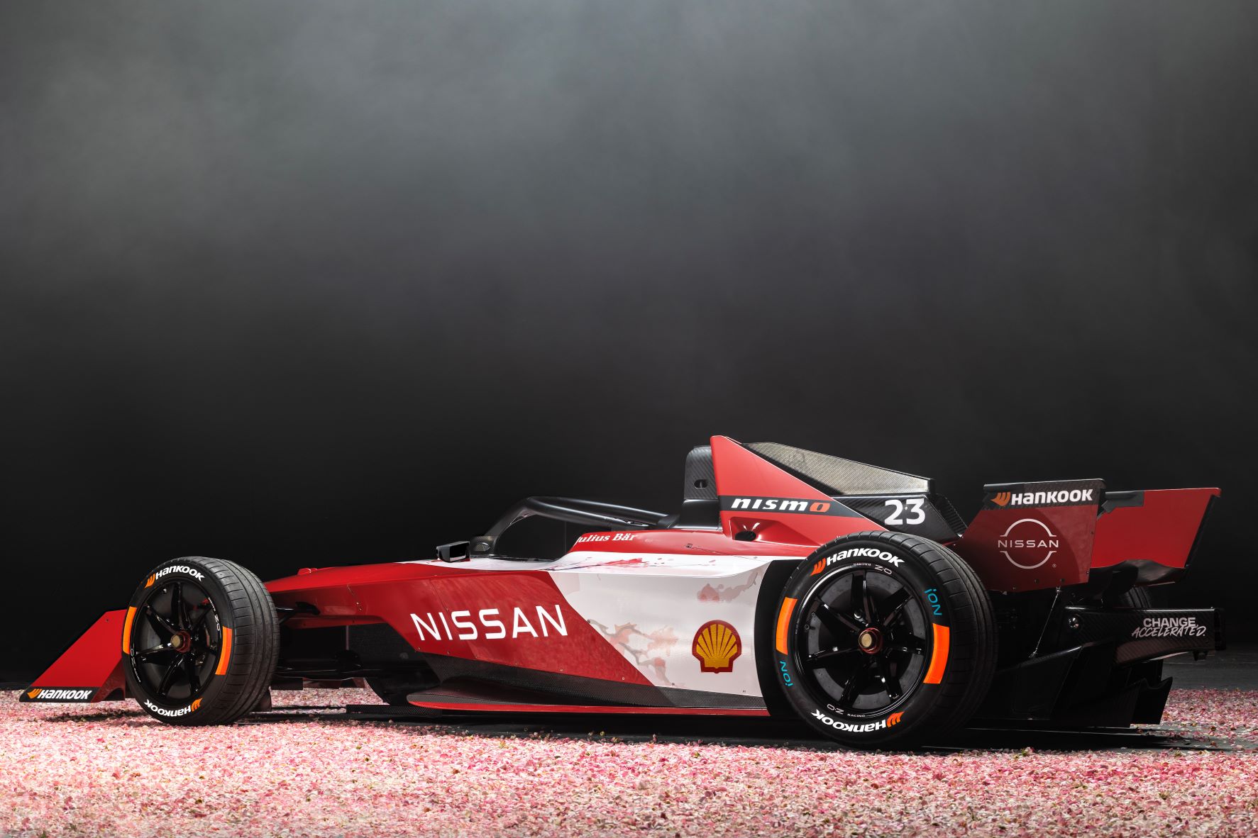 Rear three quarters view of the Team Nissan Formula E Gen3 racecar in red and white.
