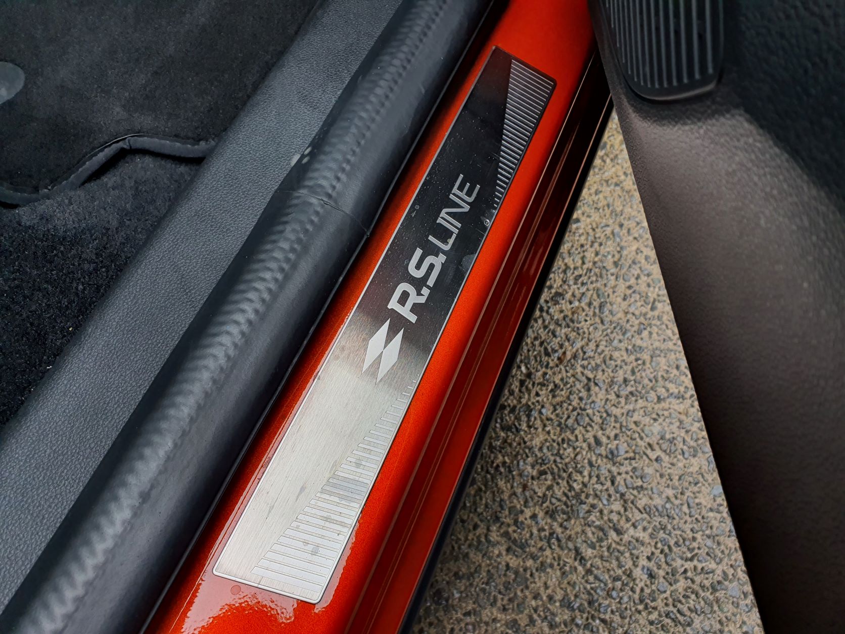 R.S Line treadplates on the interior of a Valencia Orange Renault Arkana R.S Line.