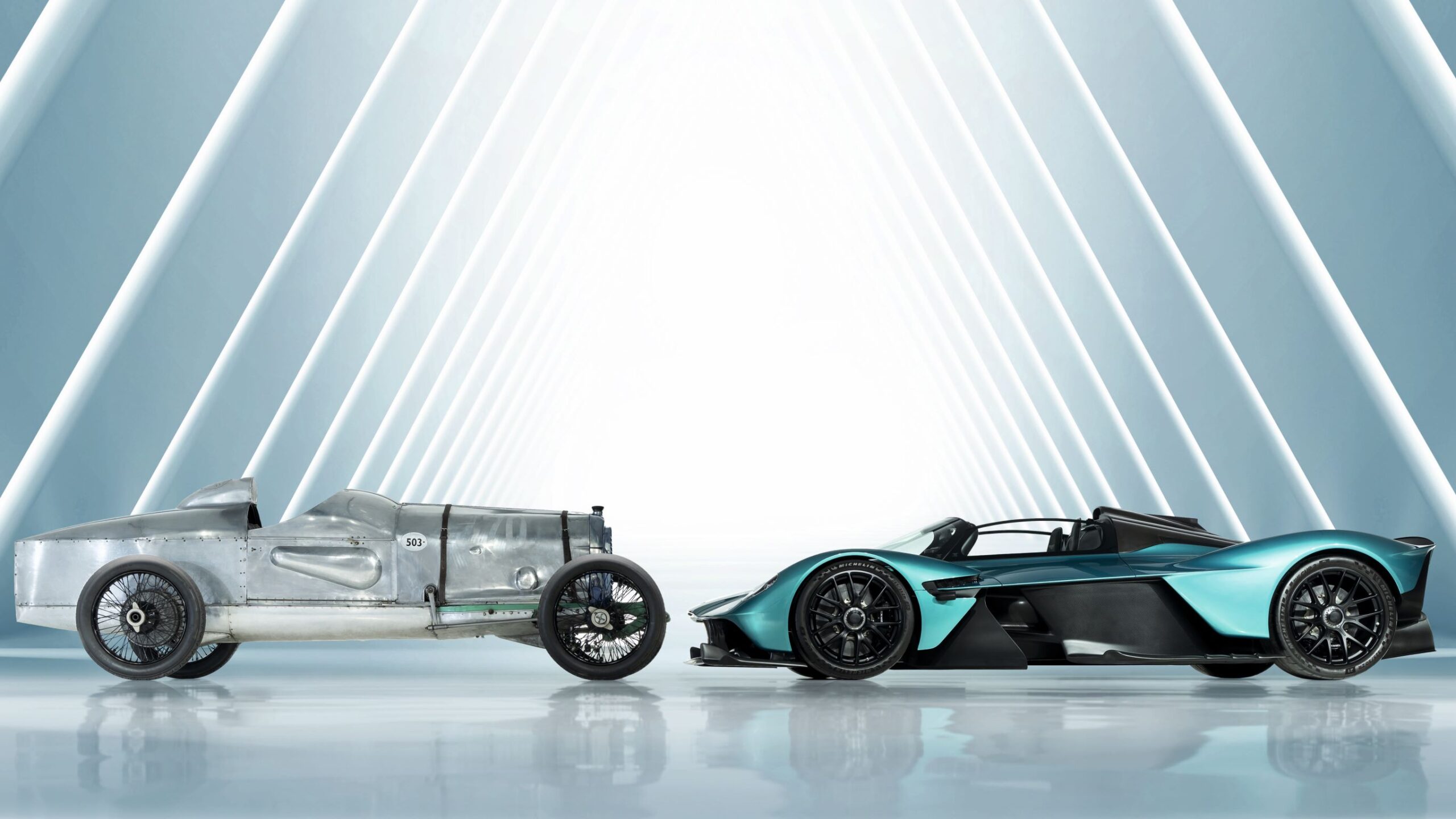 Side view of an Aston Martin Valkyrie on the right and an Aston Martin racer Razor Blade in silver on the left.