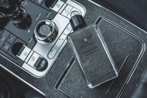 An overhead shot of a bottle of Bentley Momentum Unbreakable Eau De Parfum on the centre console of a Bentley