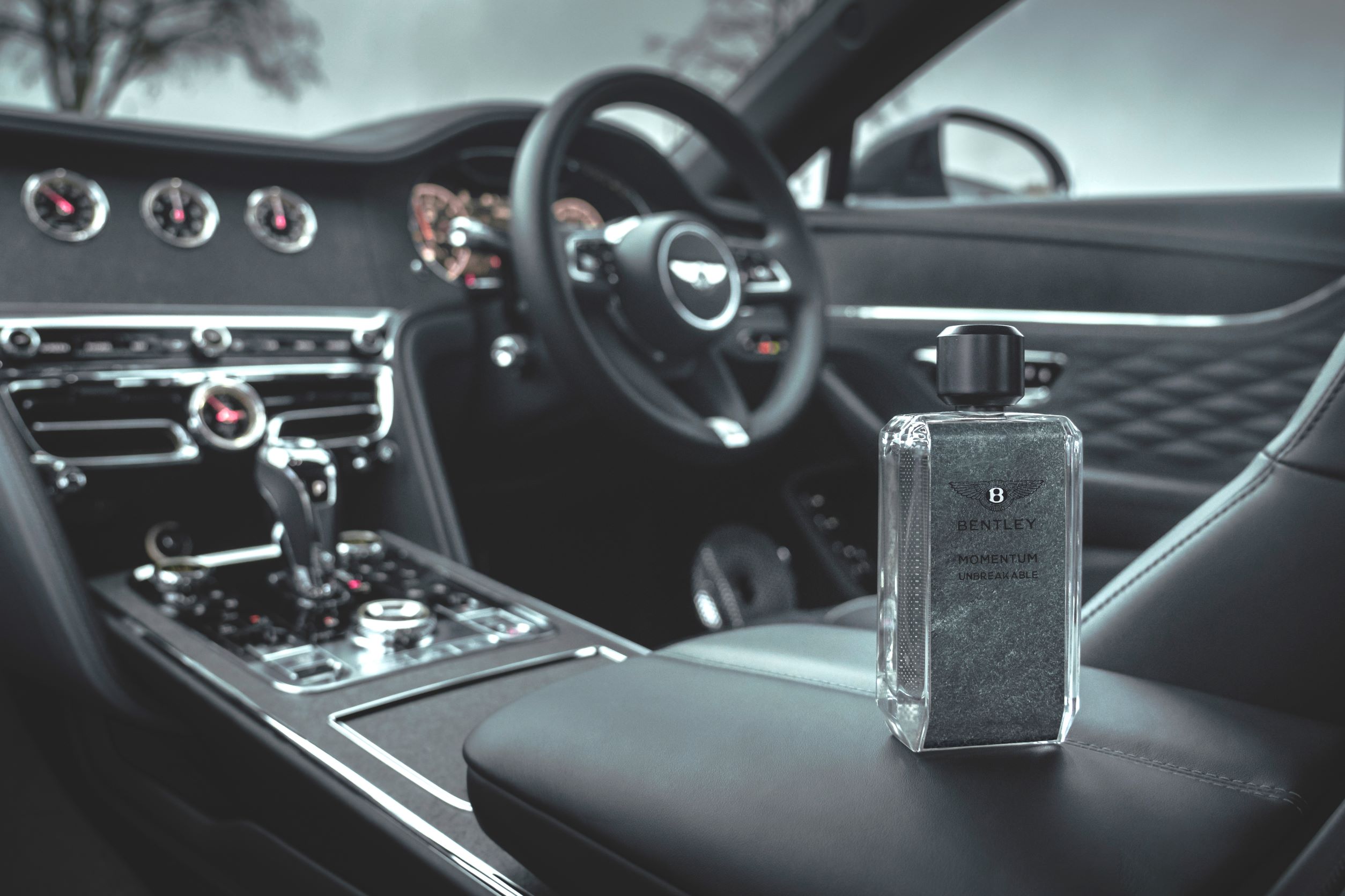 A photo of a bottle of Bentley Momentum Unbreakable Eau de Parfum on the central armrest of a Bentley.