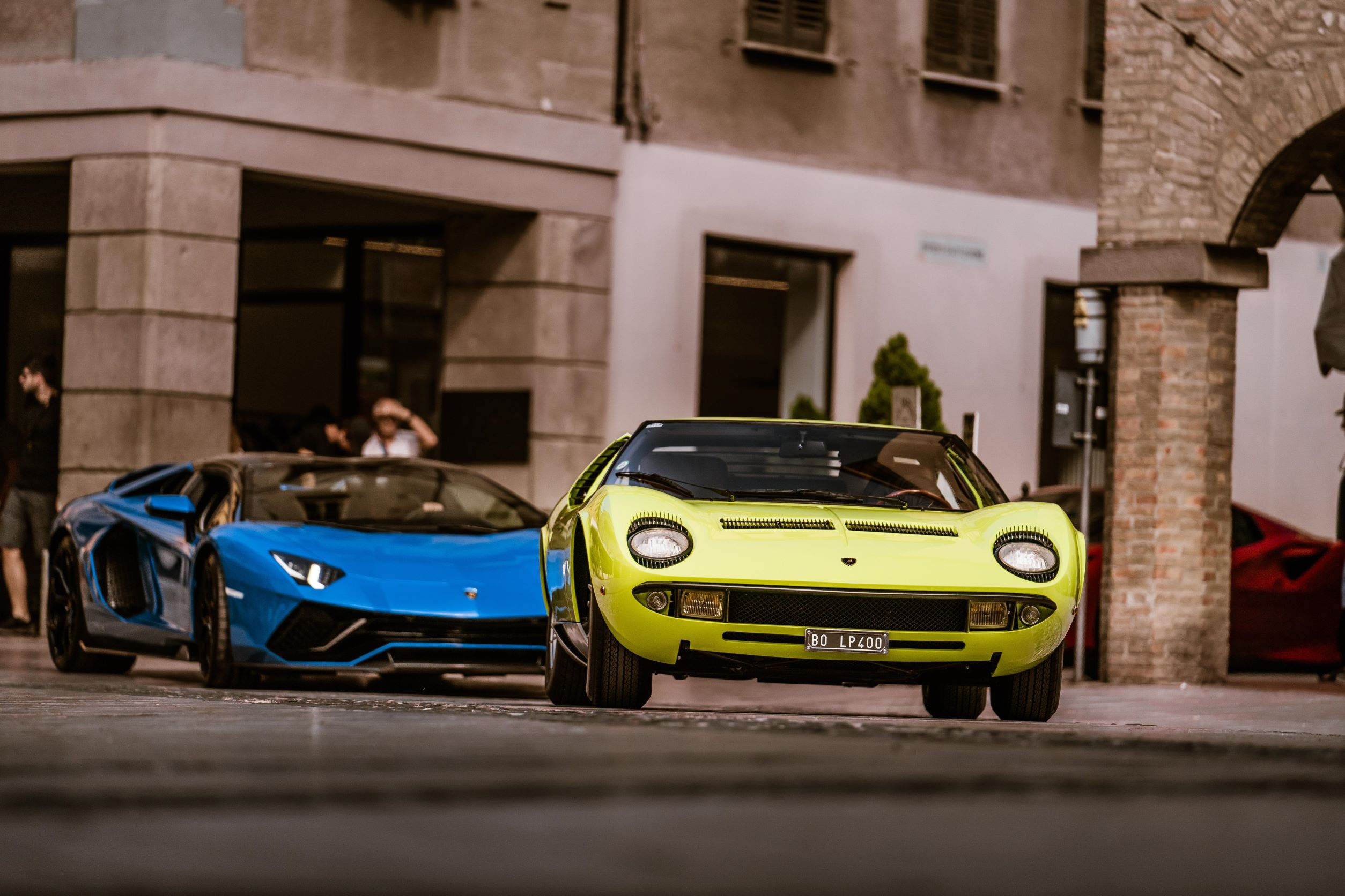 A Lamborghini Miura P400 followed closely by a blue Lamborghini Aventador S.