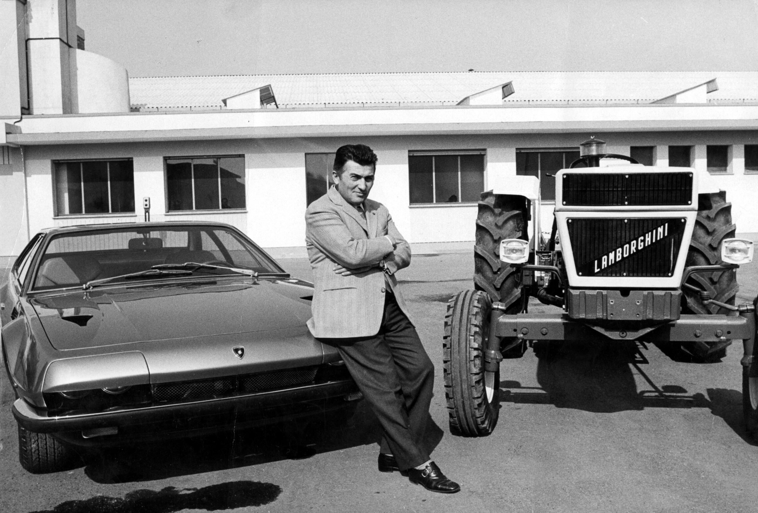 An old photo of Ferruccio Lamborghini with a tractor and car bearing his name.