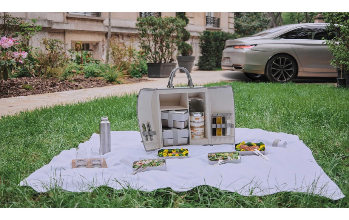 A promo shot of the DS Automobiles branded picnic hamper on a picnic blanket in a park.
