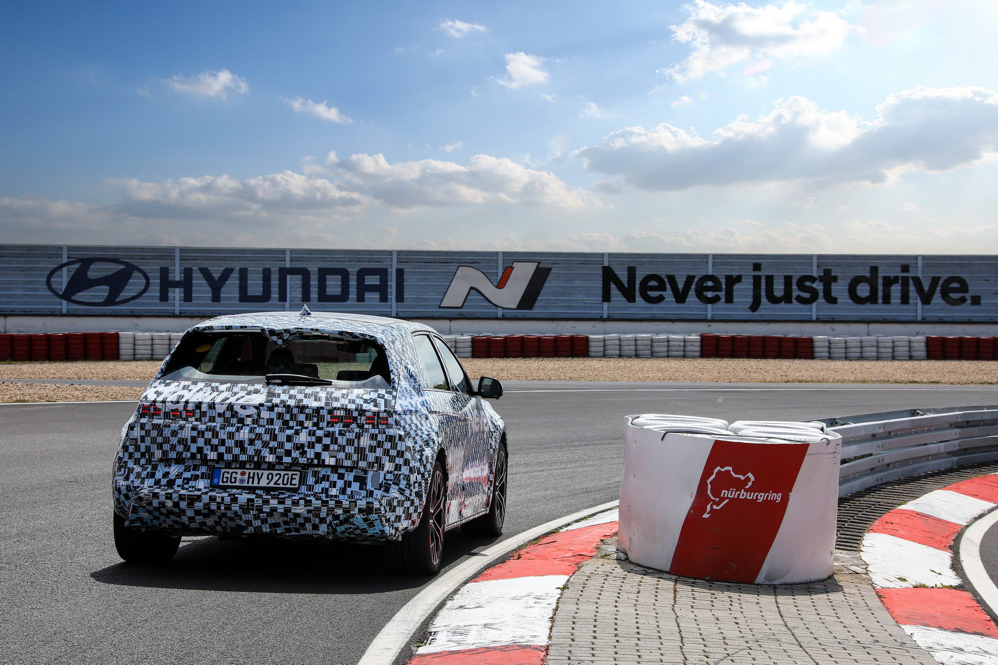 A promo shot of a Hyundai IONIQ 5 N on the Nurburgring test facility with Hyundai N hoardings in the background. 