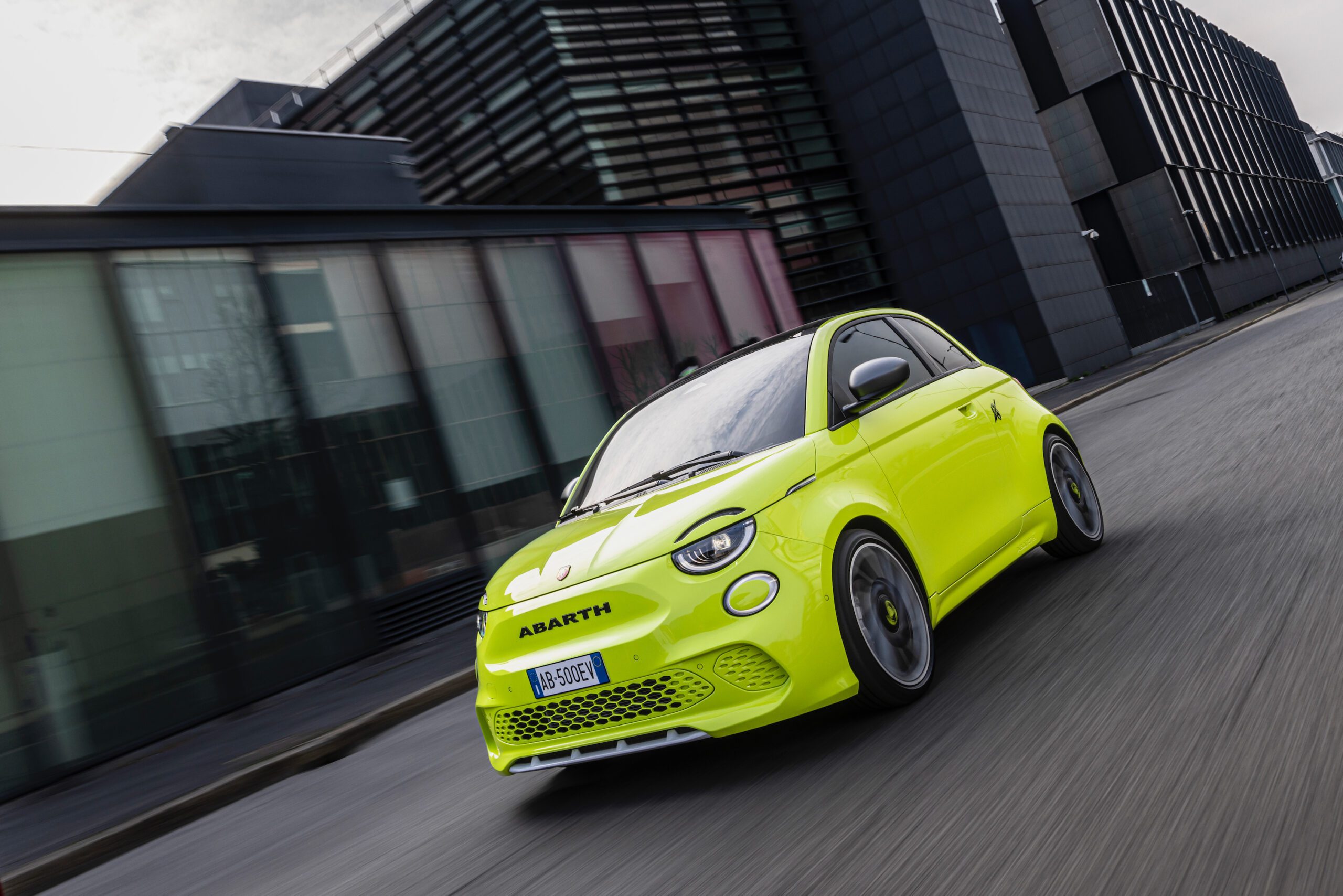 A rolling shot of a bright green Abarth 500e hot hatch