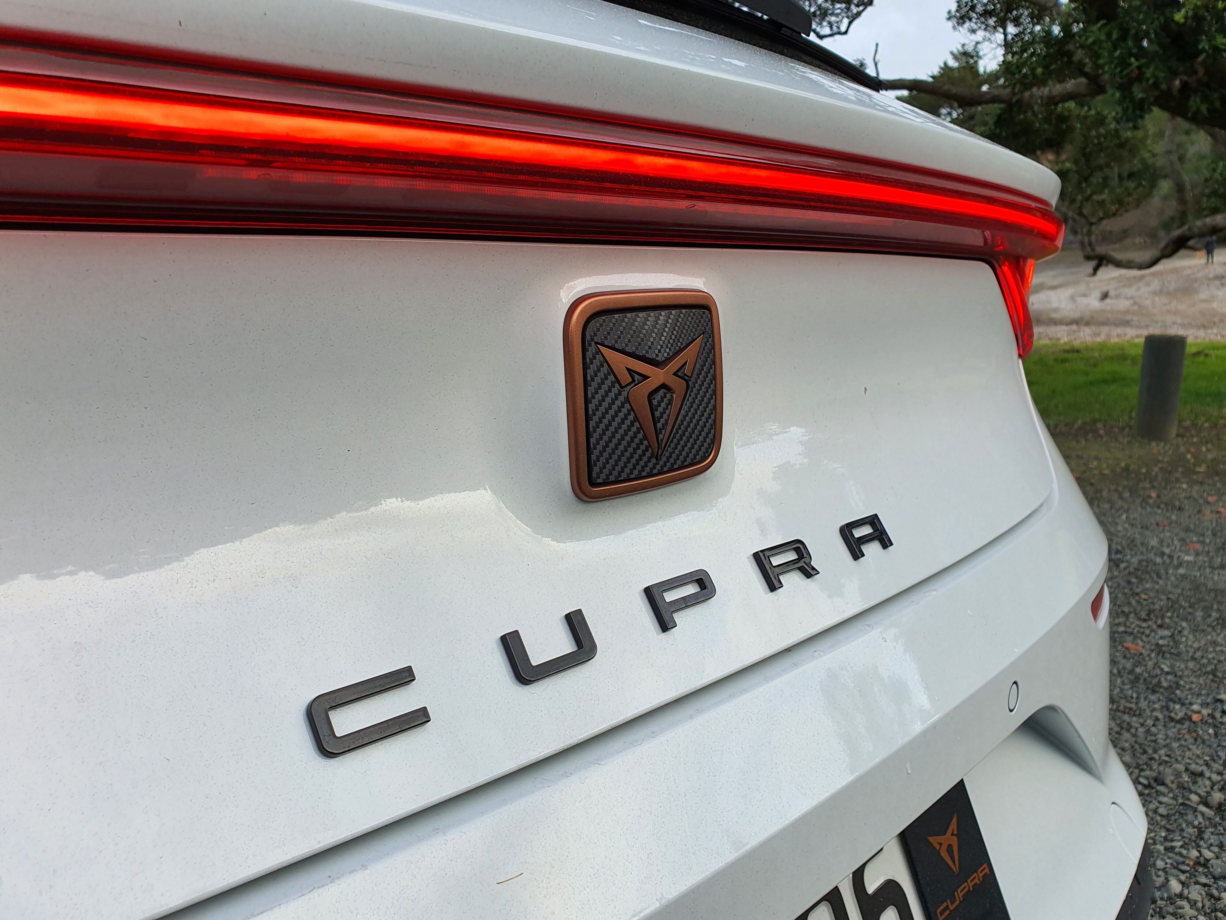 Close-up of the Cupra logo on the road of the 2023 Leon V in 'Nevada White'