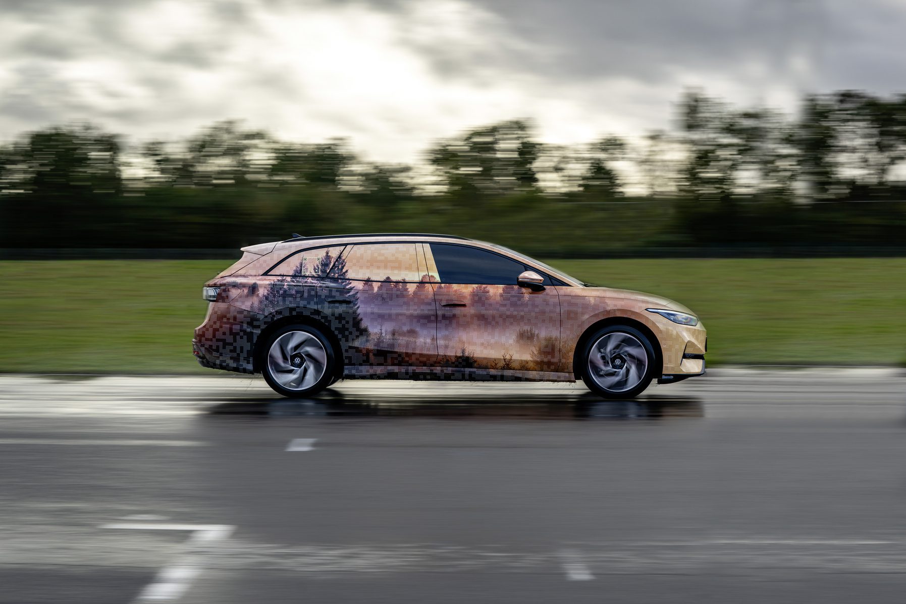 Side on view of a Volkswagen ID.7 Tourer in camouflage on the move.