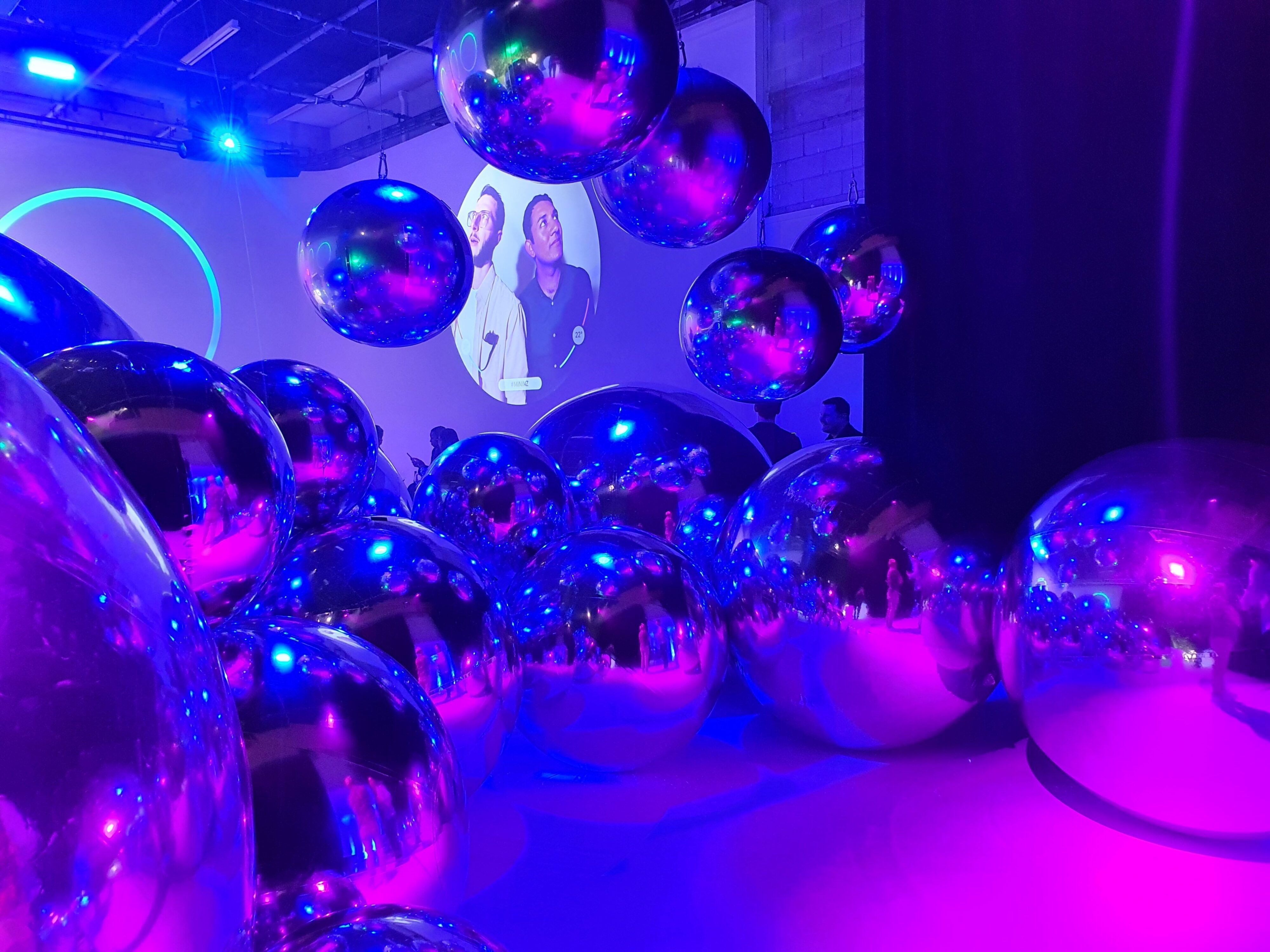 A dimly lit photo of the inside of Studio 230, Ponsonby, Auckland. In frame are large reflective spheres with a photo of Matthew and Harry from Tarmac Life projected on the wall.