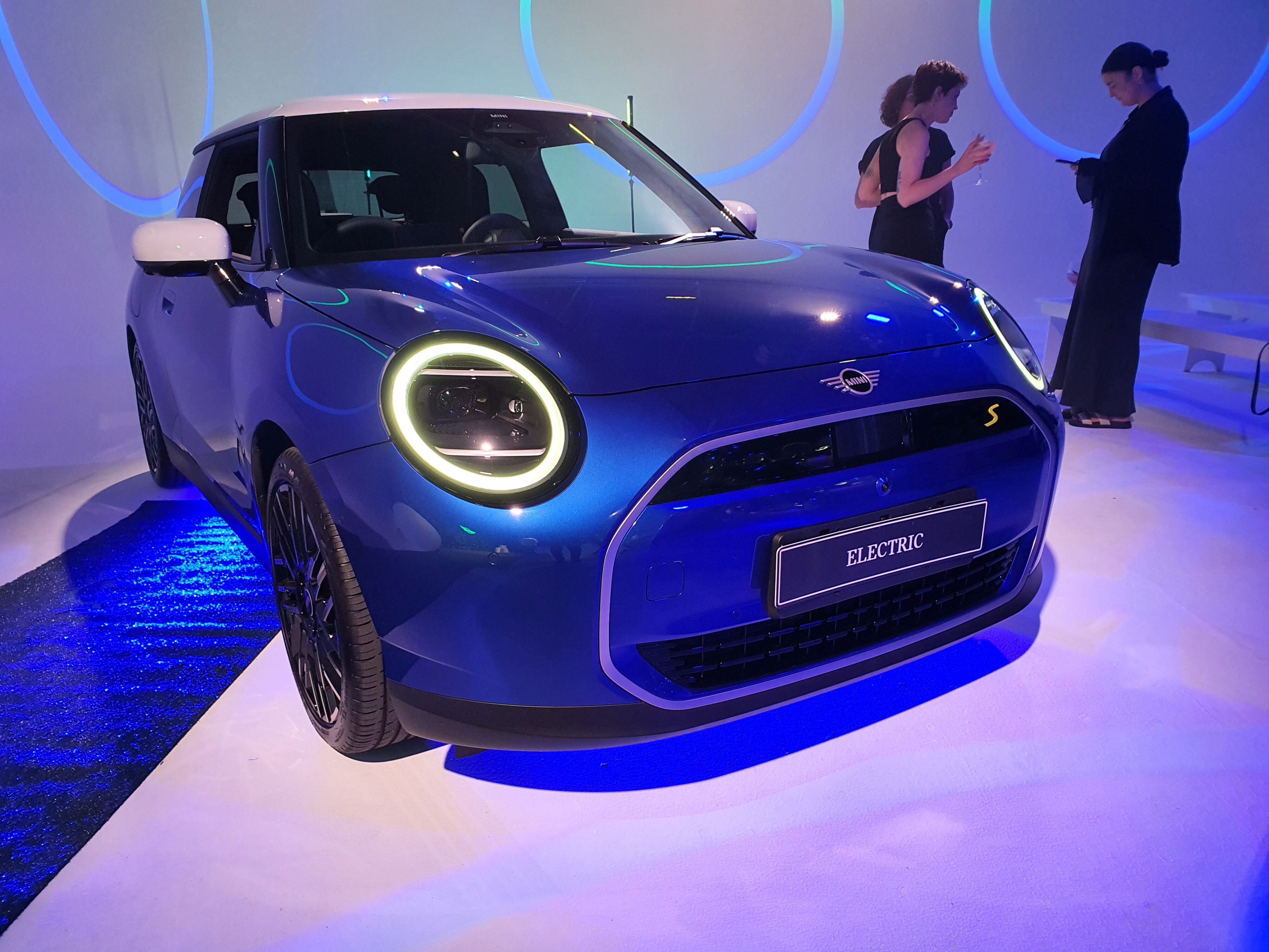 A front three quarters view of a 2024 Mini Cooper S E hatchback in blue with a white roof.
