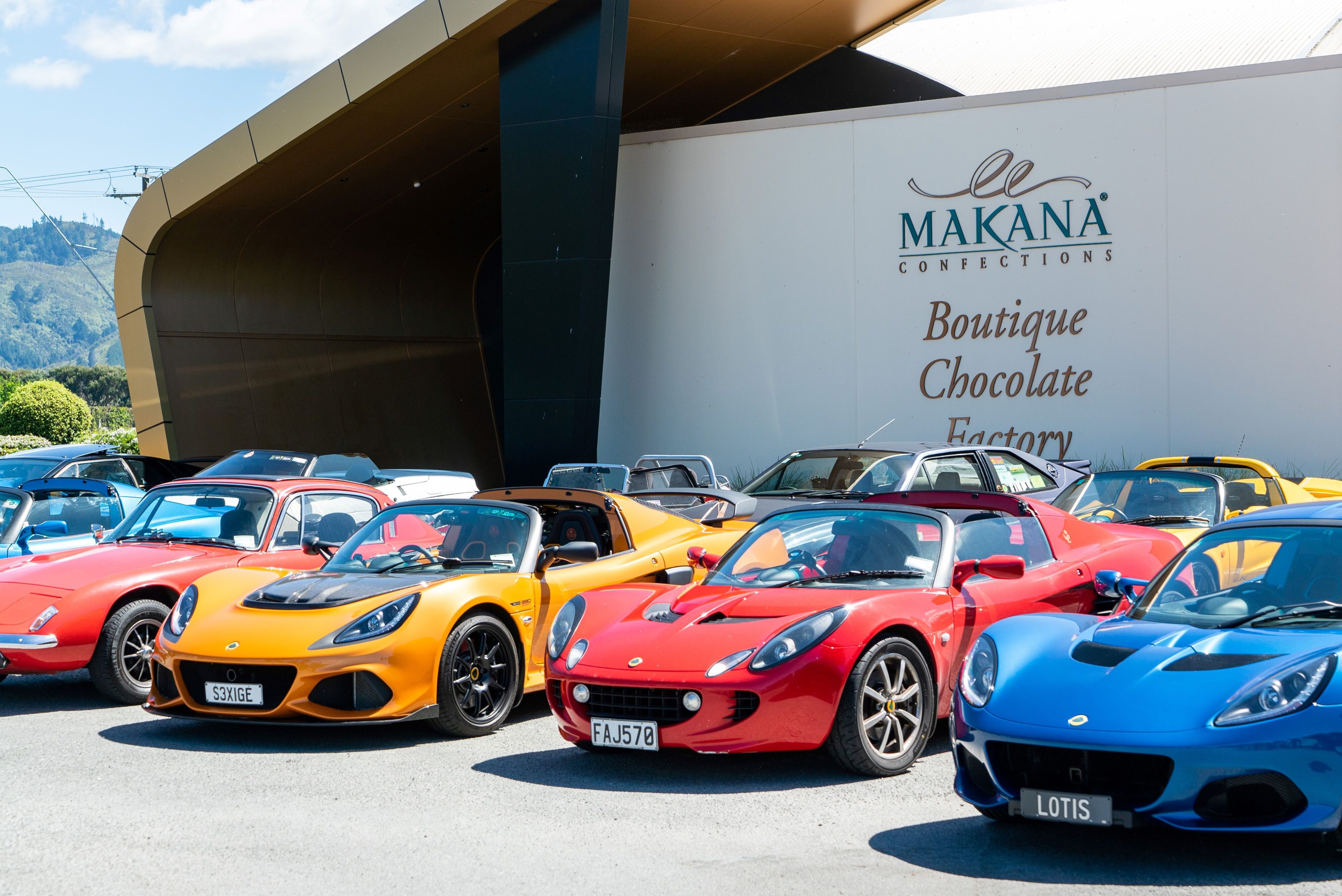 An array of Lotus vehicles parked outside Makana Confections in New Zealand. This was a stop during the brand's 75th Anniversary celebrations.