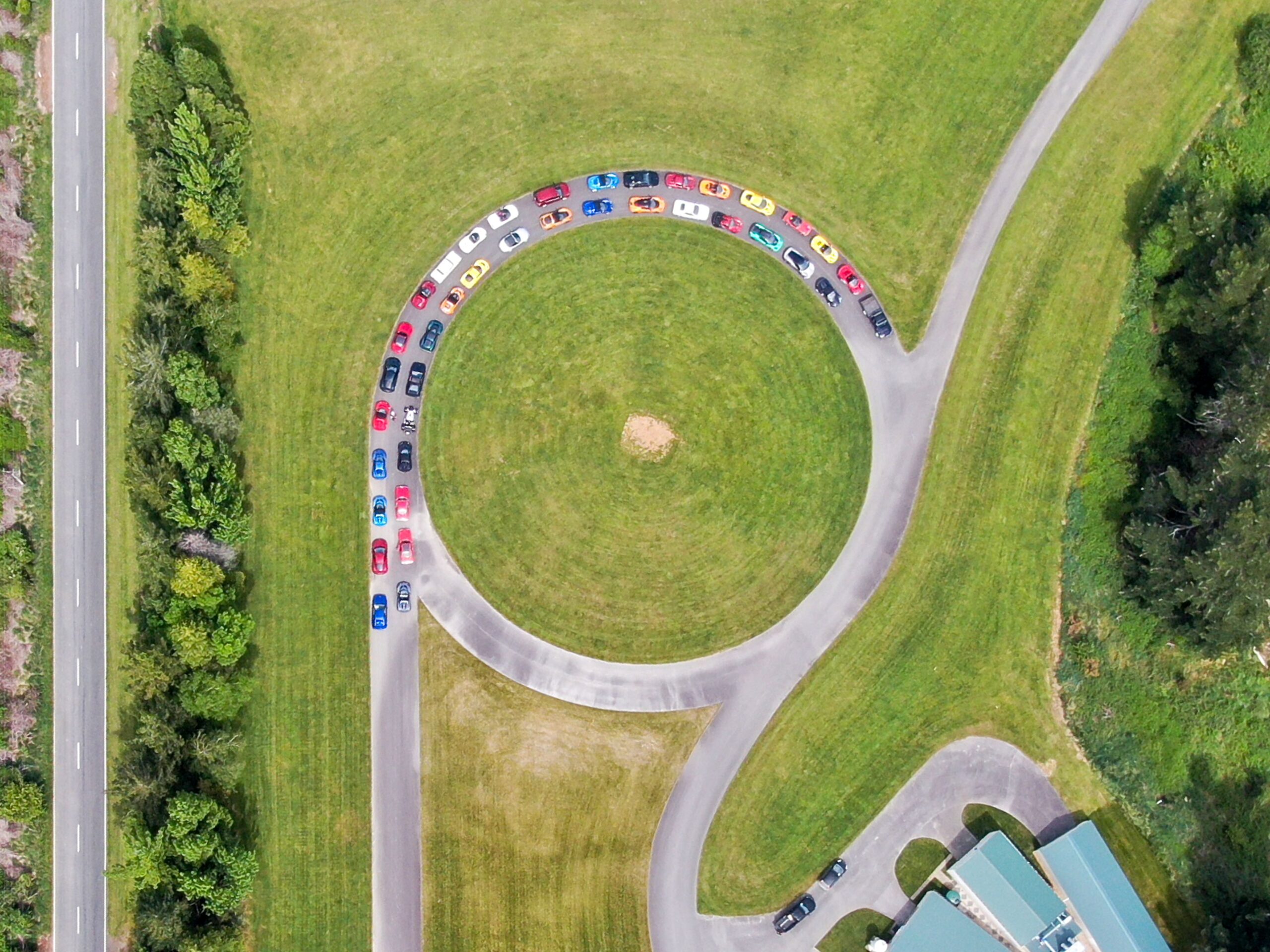 A drone shot of several Lotus vehicles parked in a display formation at Rodin Cars' HQ in New Zealand. The photo opportunity was taken on the Club Lotus NZ 75th anniversary NZ tour.
