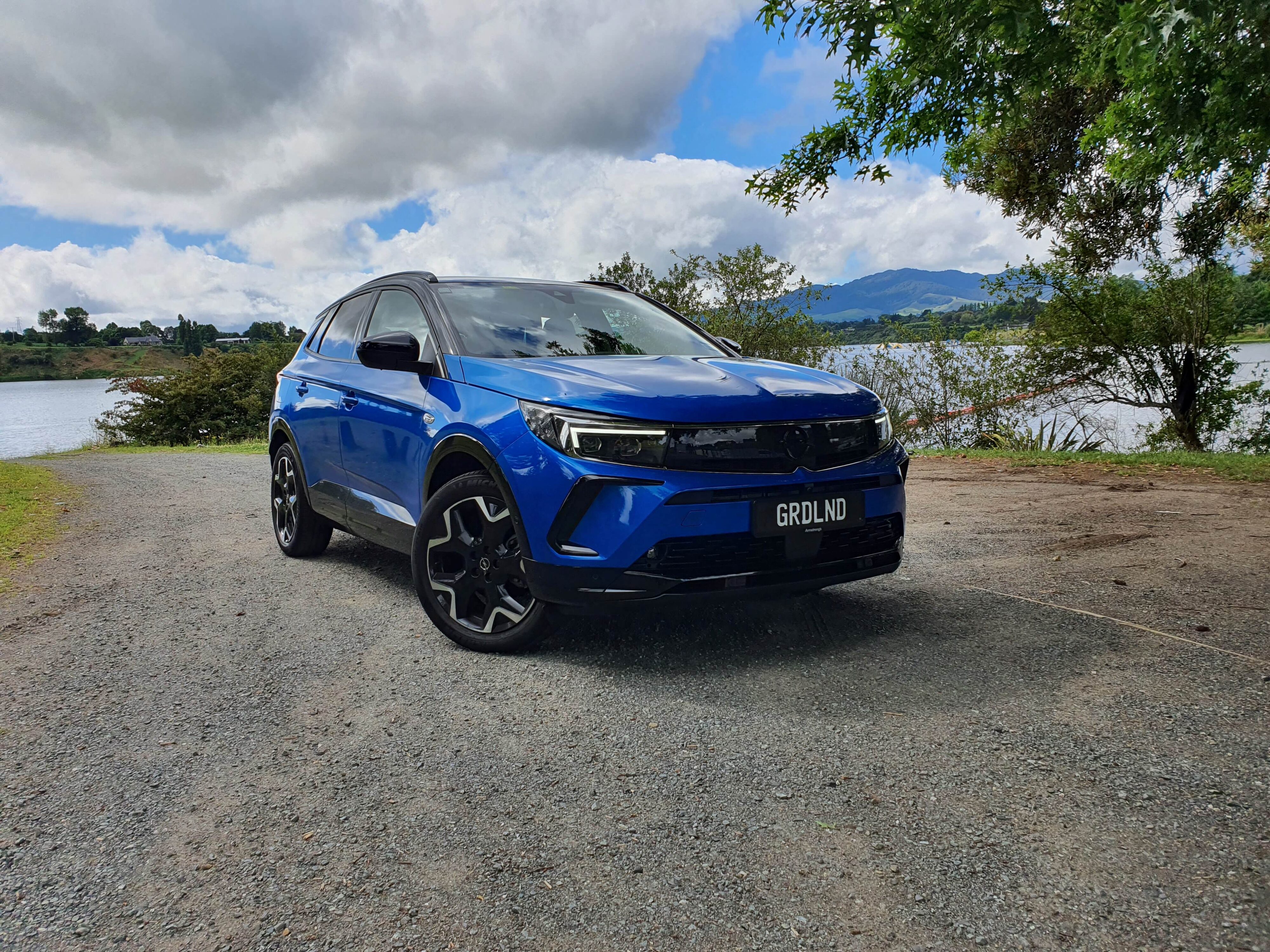 Front three quarters view of a Cobalt Blue Opel Grandland SRi on the banks of Lake Karapiro, Waikato, New Zealand.