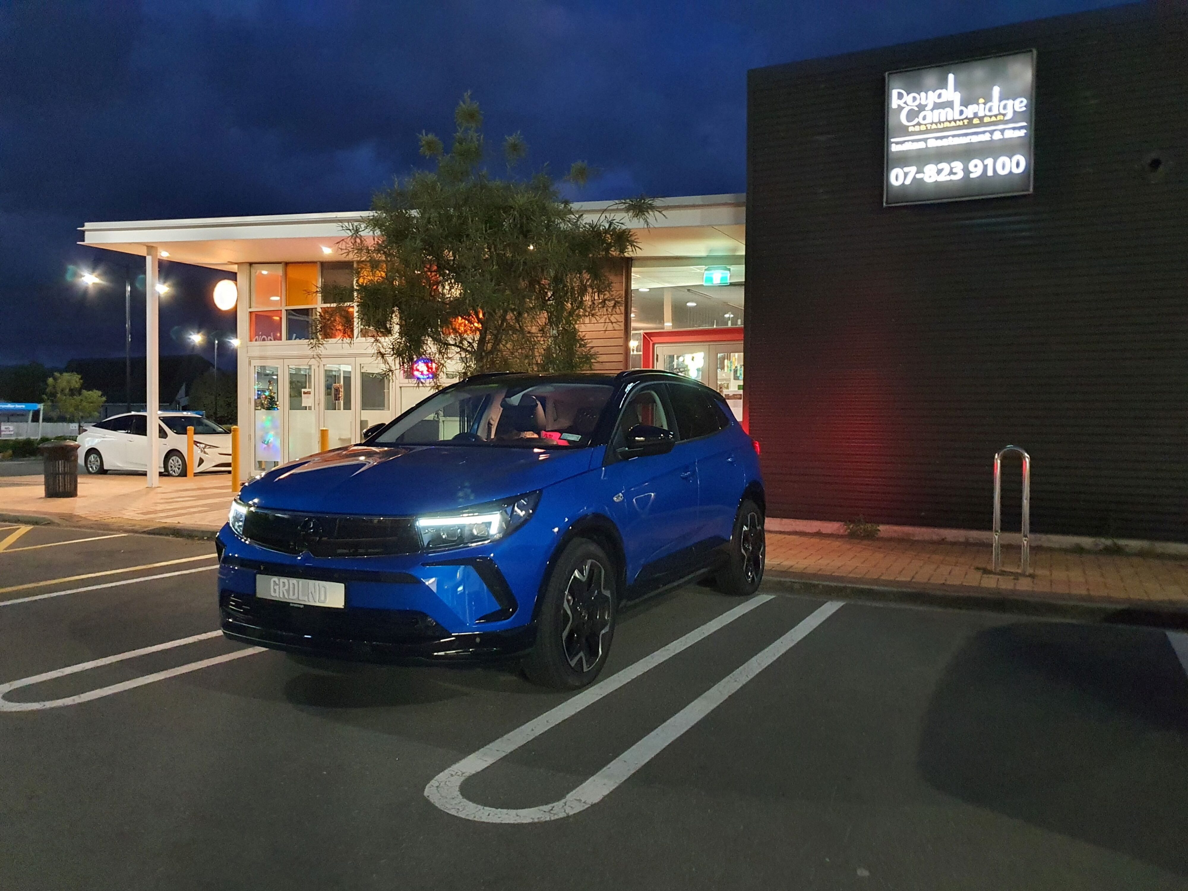 Nighttime photo of a Cobalt Blue Opel Grandland SRi outside the Royal Indian Restaurant, Cambridge, Waikato, New Zealand.