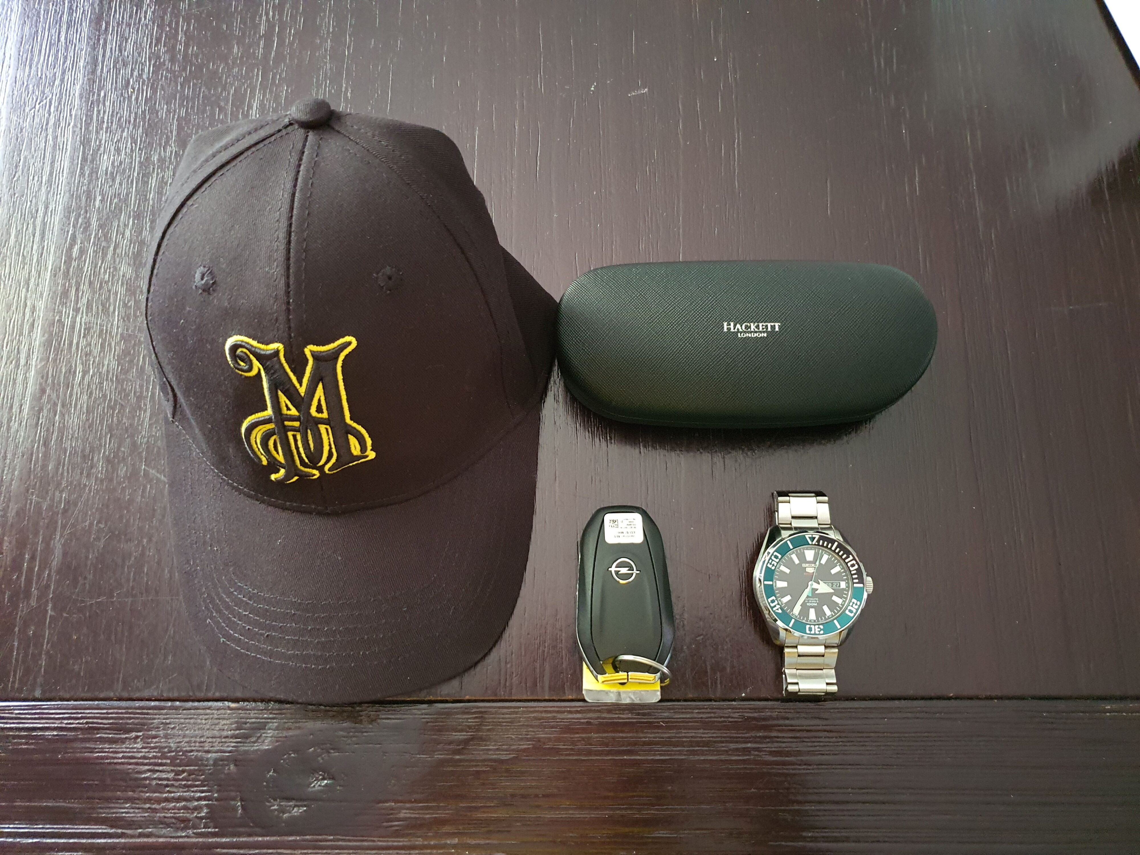 Matthew D'Souza's road trip essentials. Pictured is a black Meguiars cap, Hackett Harrow sunglasses, Opel car keys and a Seiko 5 Sports watch.