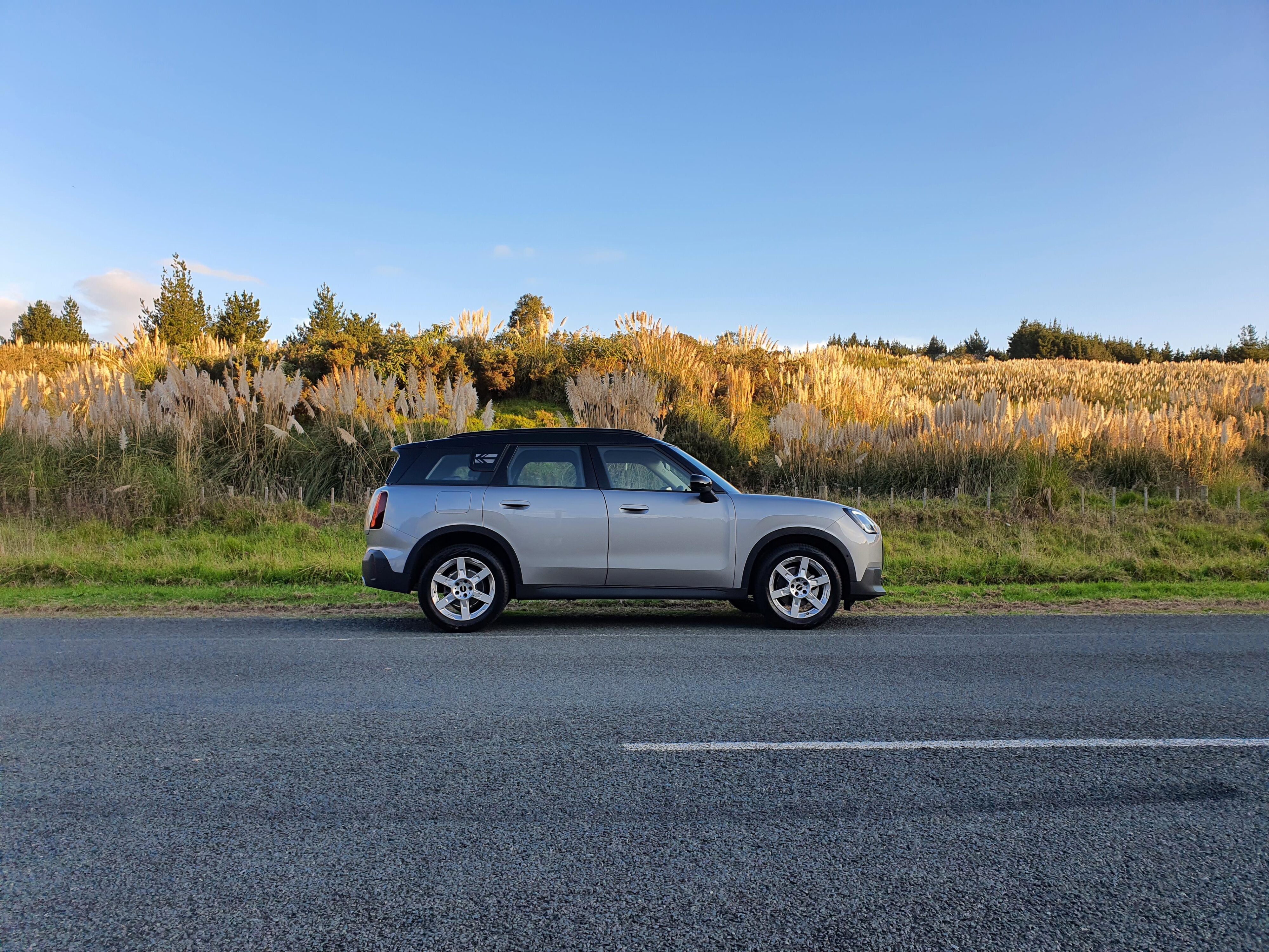 Side on view of a 2024 Mini Countryman C Classic in Silver at sunset with a natural background.