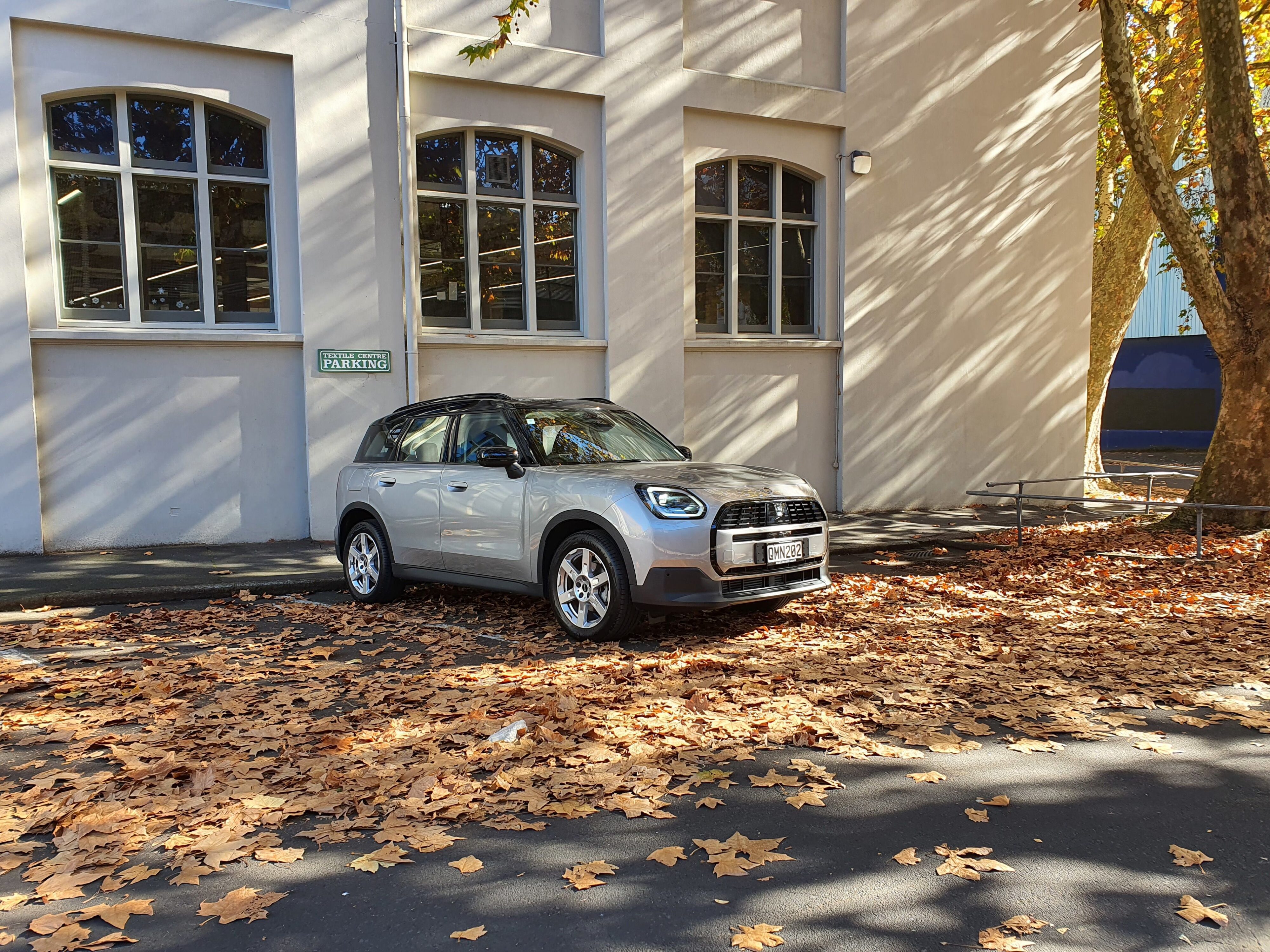 Front three quarters view of a 2024 Mini Countryman C Classic with a heritage building in the background.