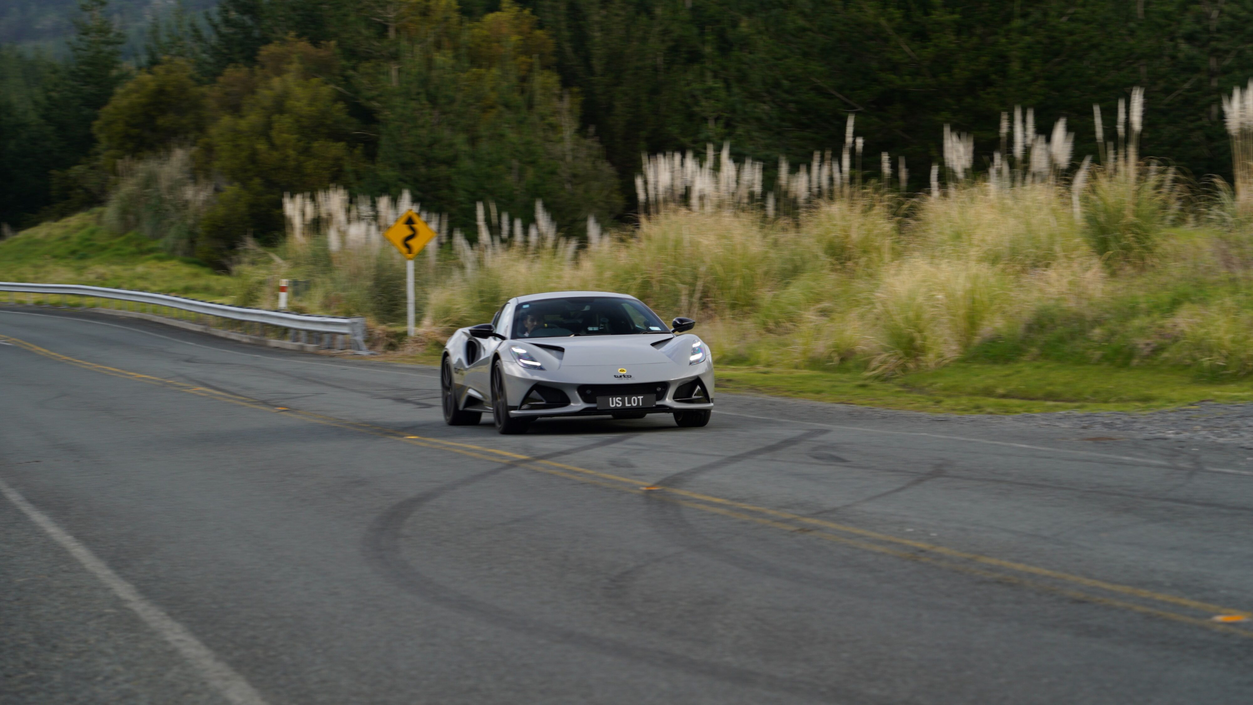 A 2024 Lotus Emira i4 Turbo in Nimbus Grey accelerating uphill. 