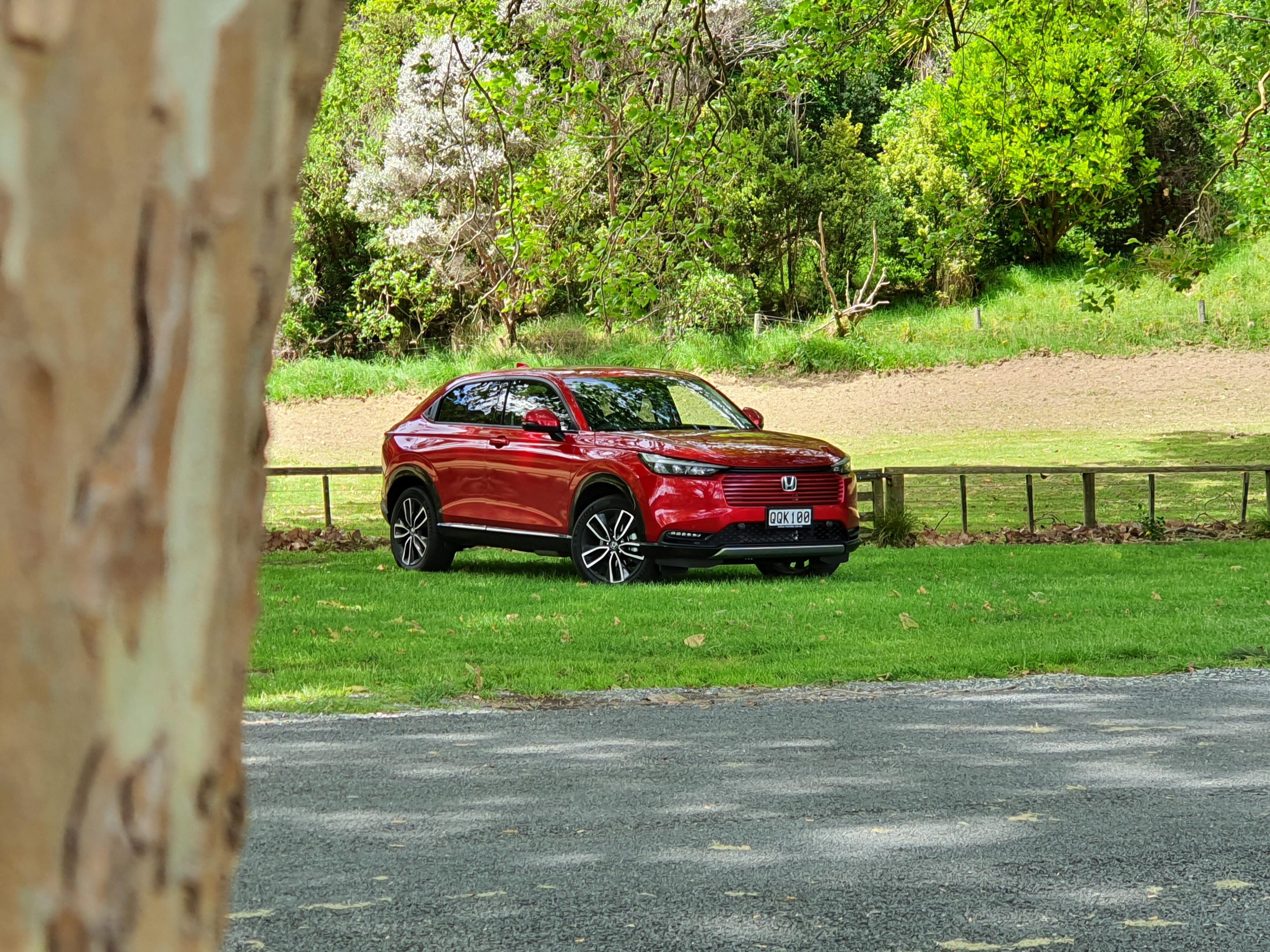 Front three quarters view of a 2024 Honda HR-V in Metallic Red at Shakespear Park, Auckland.