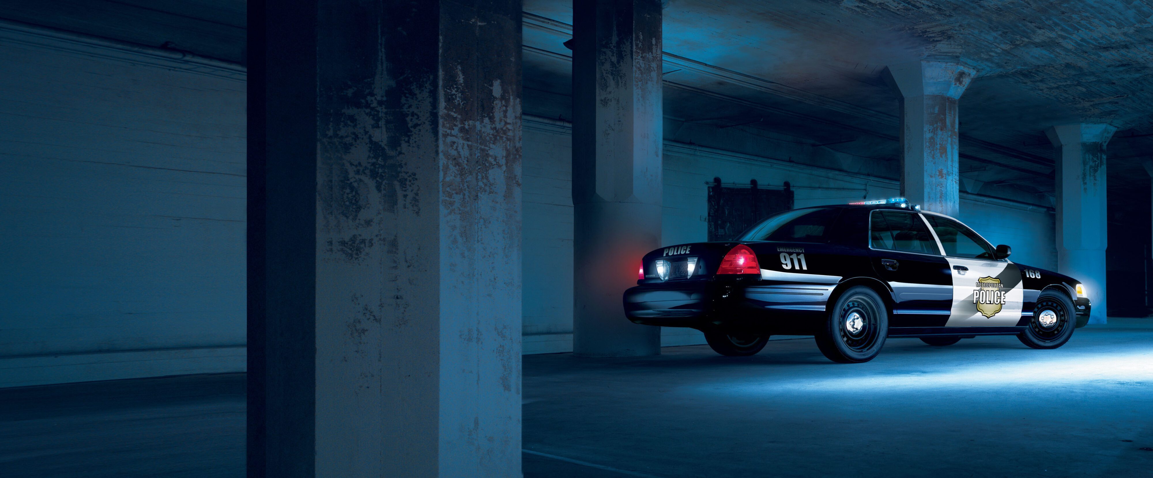 A photo of a Ford Crown Victoria police car in a dimly lit underground carpark.