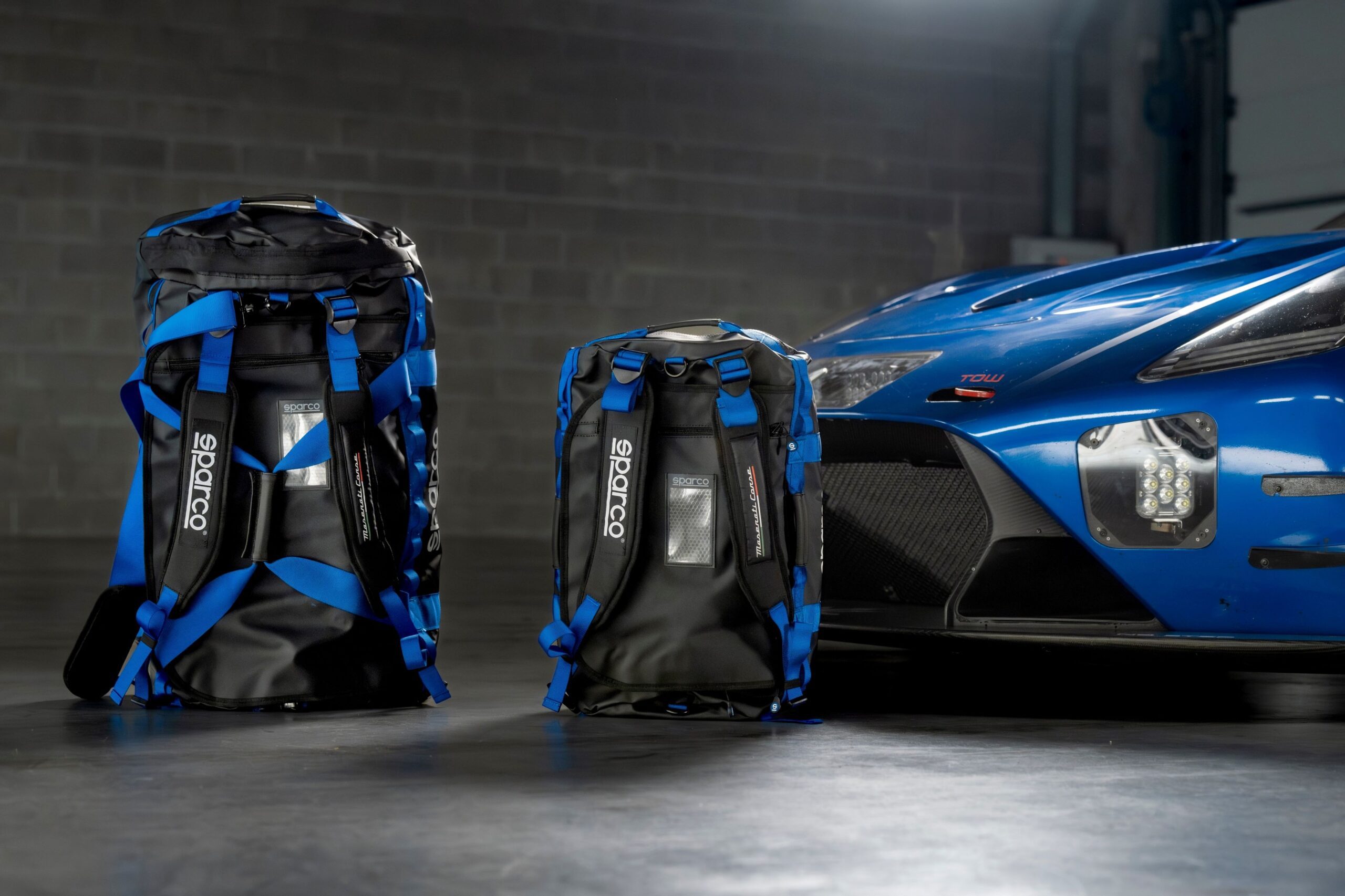 Maserati Sparco duffel bags pictured with a Maserati racecar.