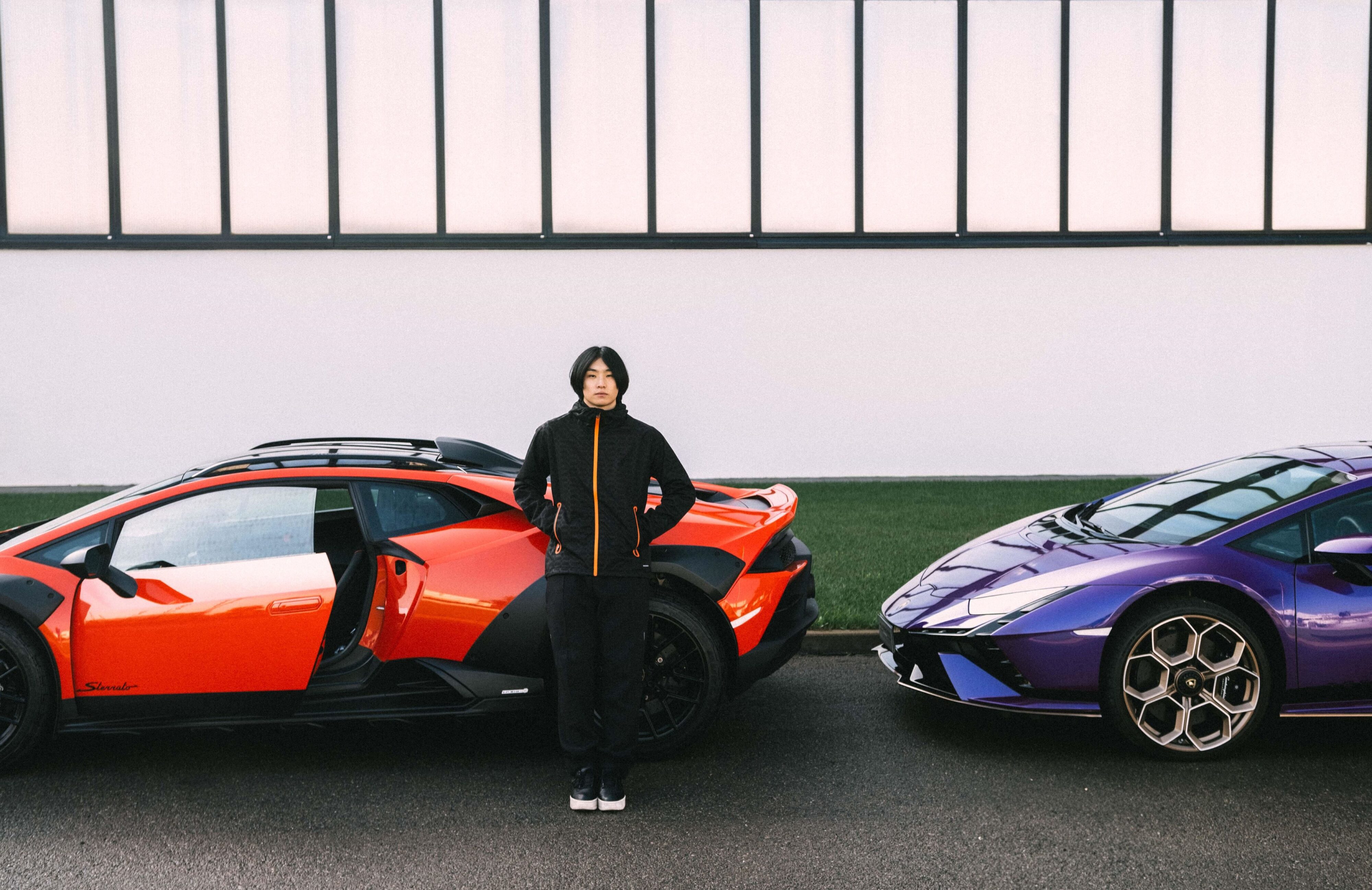 A model poses in the new activewear collection from Lamborghini and Macron with two Lamborghinis in the background.