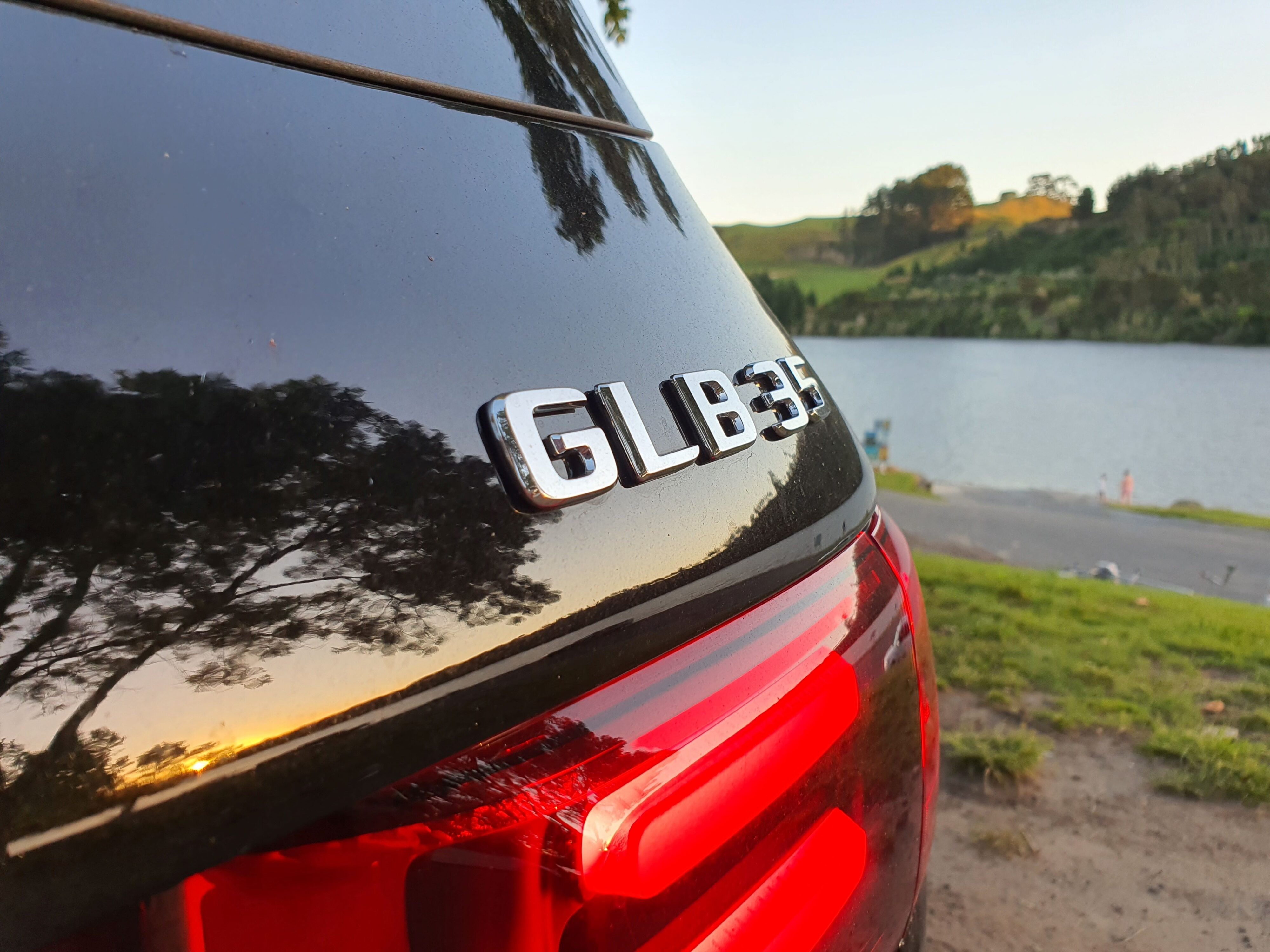 GLB 35 badging on the rear of a 2024 Mercedes-AMG GLB 35 4MATIC in Black with the waters of Lake Karapiro, Cambridge in the background.