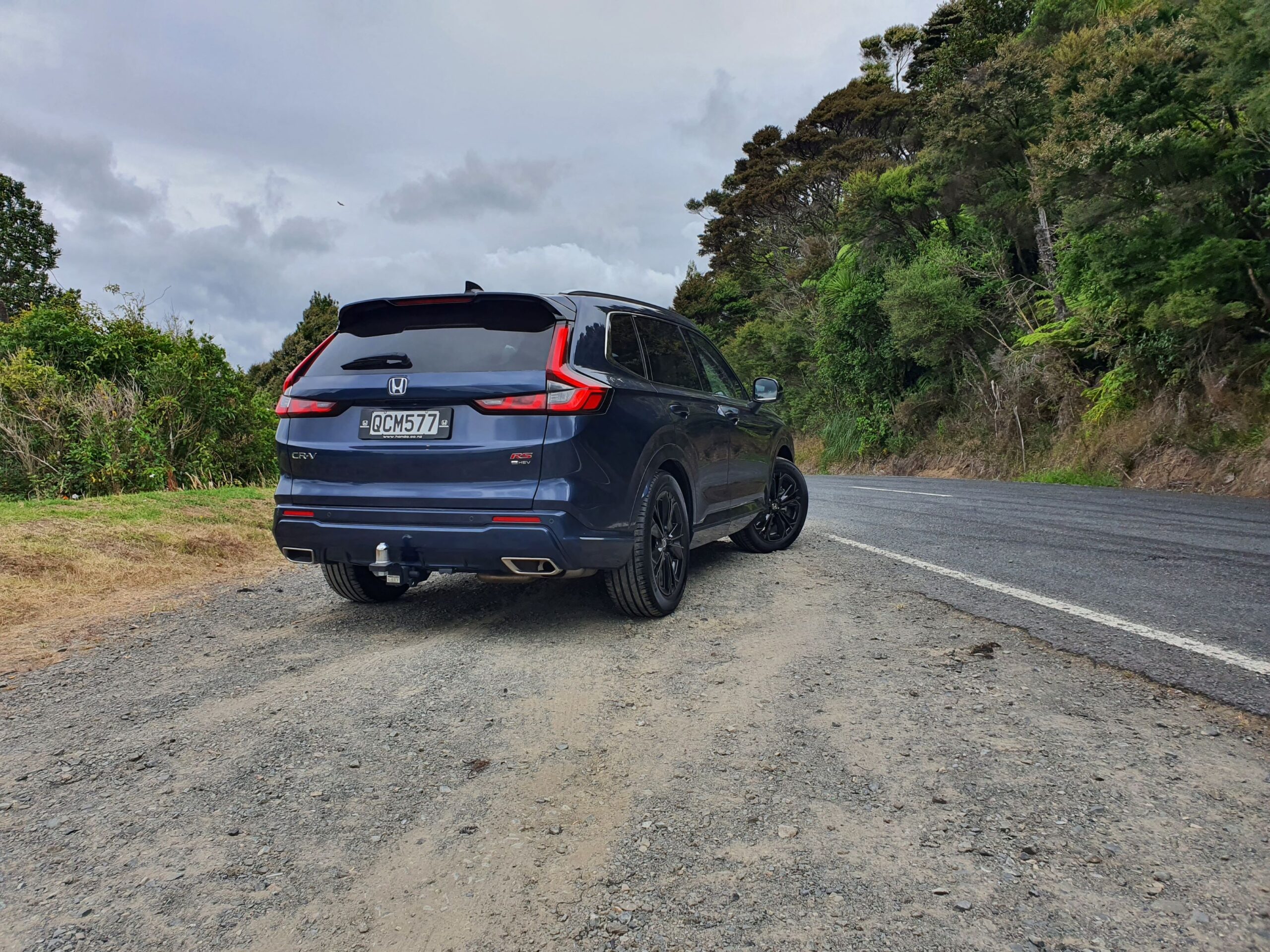 Rear three quarters view of a 2024 Honda CR-V RS e:HEV in Canyon River Blue Metallic.