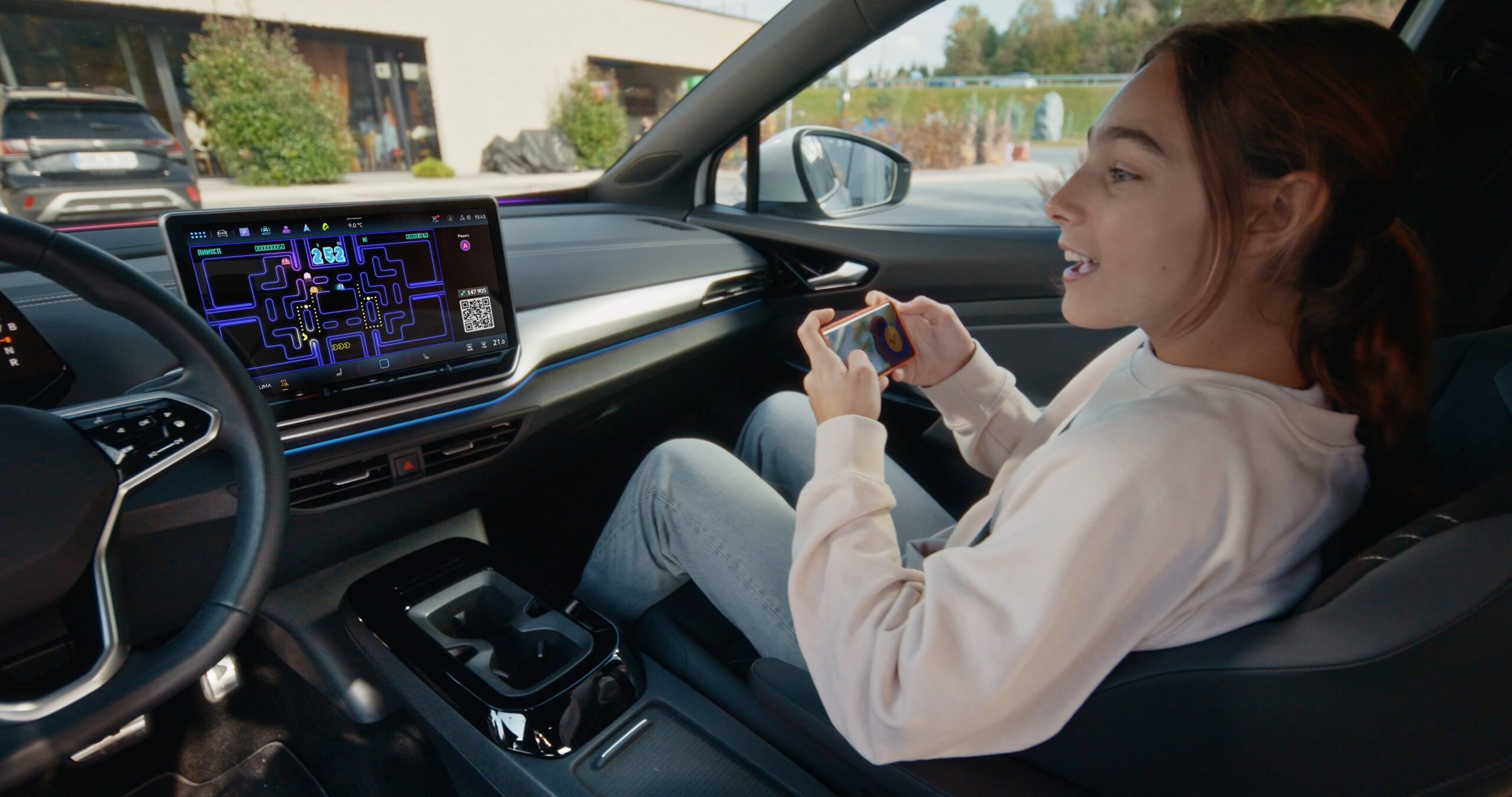 A girl plays PAC-MAN on the infotainment screen of a Volkswagen car.