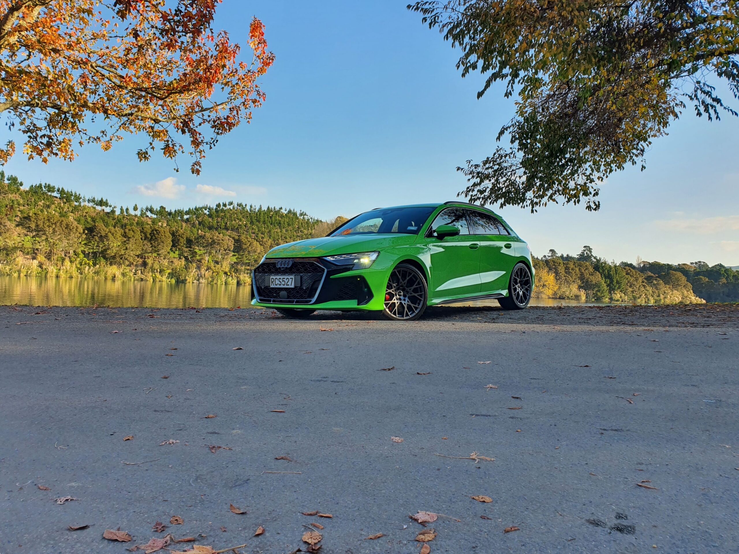 Front three quarters view of a 2025 Audi RS3 in Kyalami Green, photographed on the edge of Lake Karapiro in Cambridge.