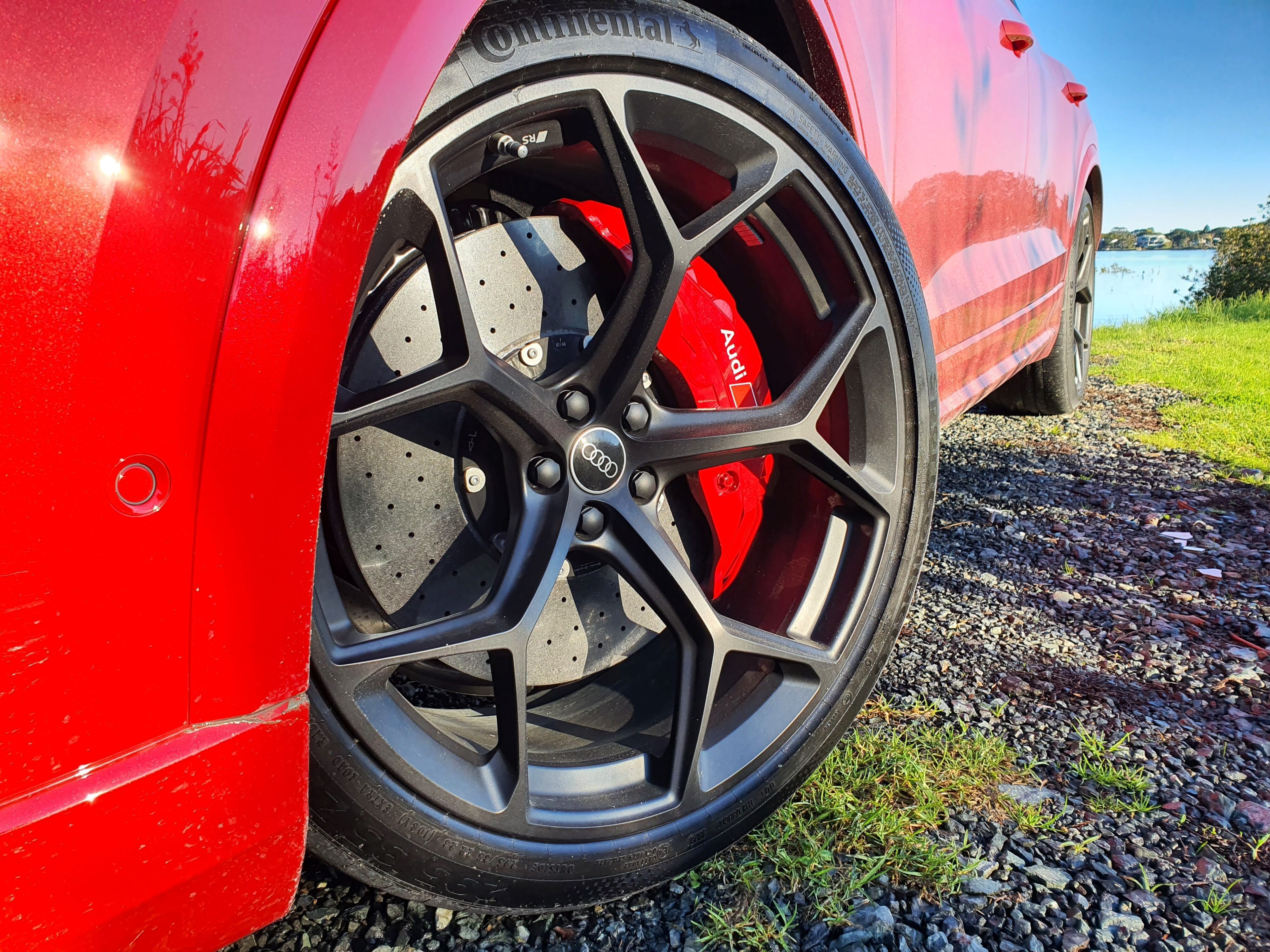 23 inch wheels and Audi Carbon Ceramic brakes photographed on a 2025 Audi RS Q8 Performance in Chili Red.