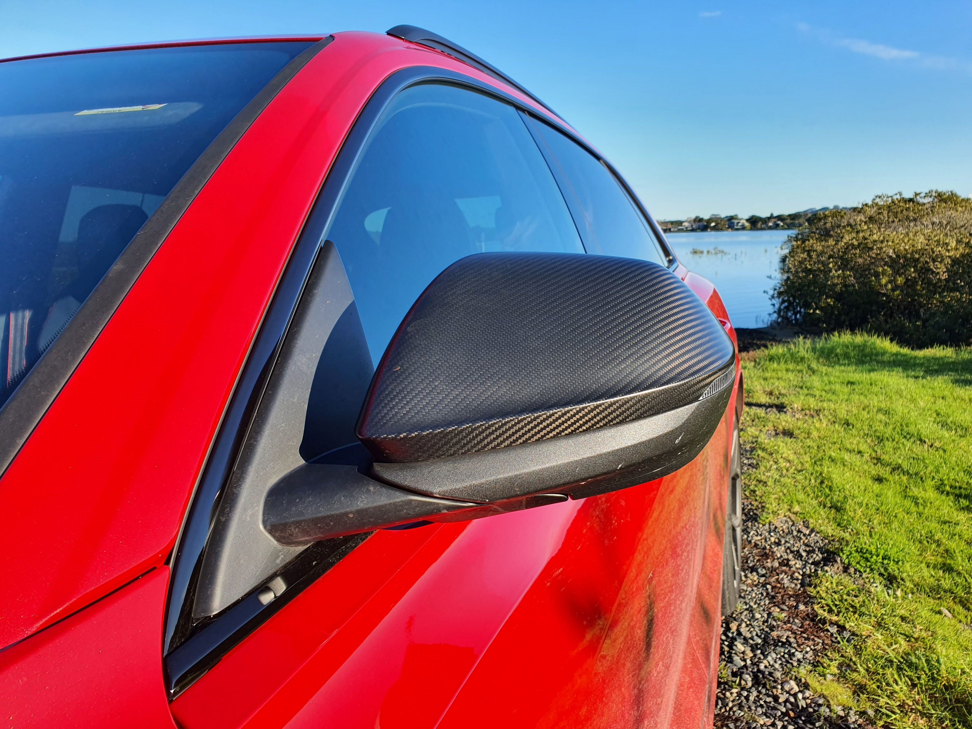 Carbon fibre mirror caps photographed on the side of a 2025 Audi RS Q8 Performance in Chili Red.