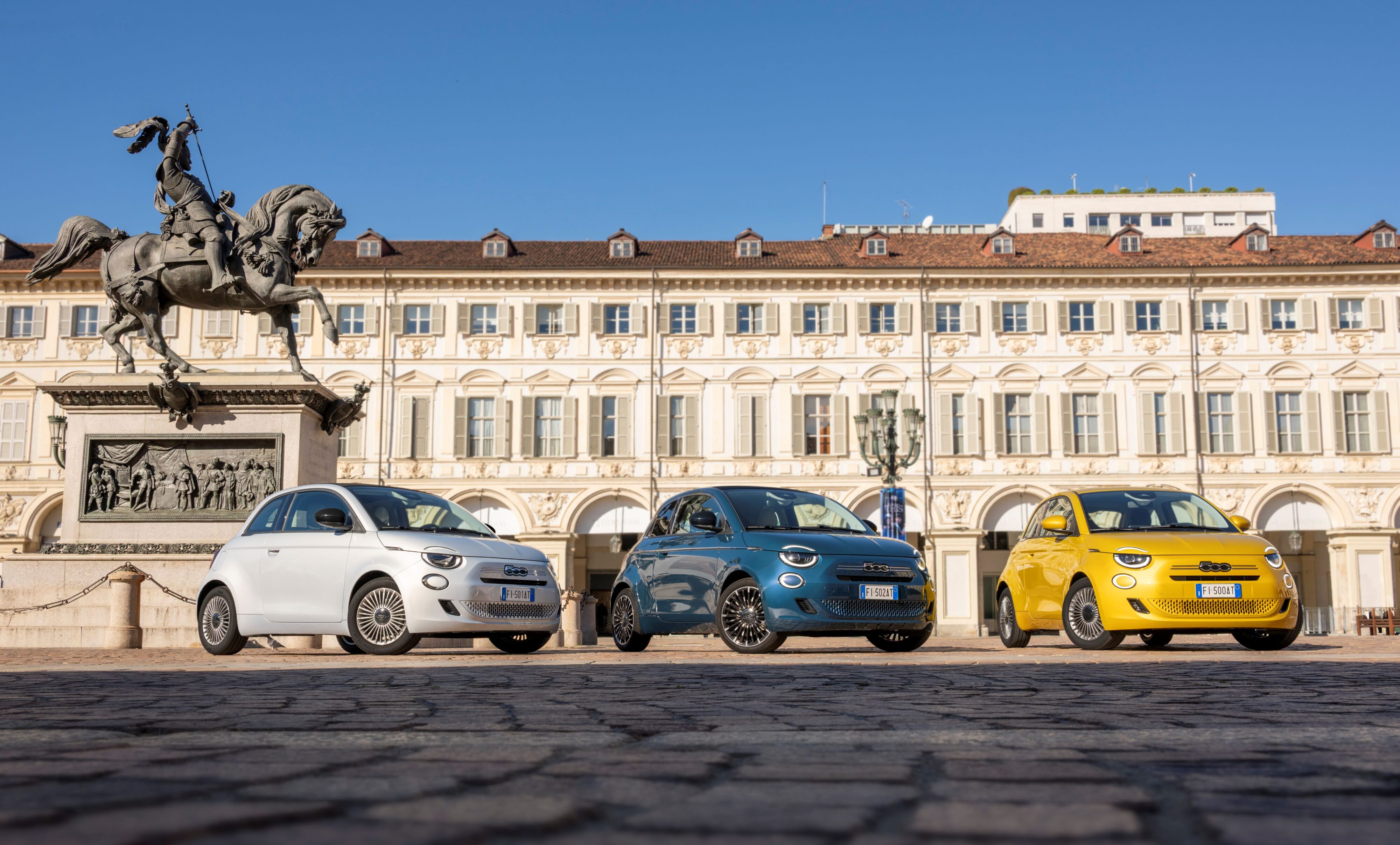 The three new Fiat 500 hybrid models lined up in front of a historic building in Turin, Italy.