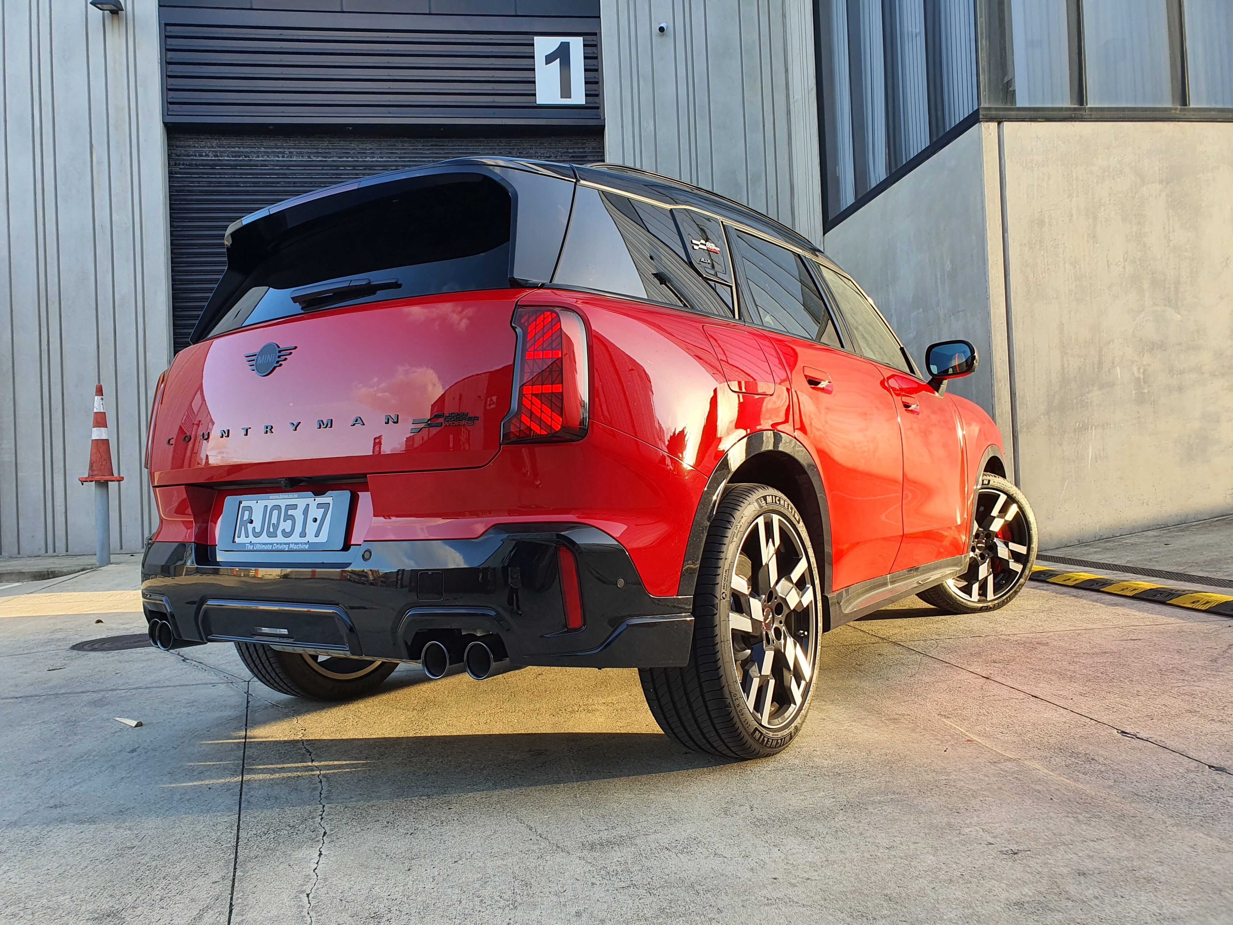 Rear three quarters view of a 2025 Mini Countryman John Cooper Works in Red with a Black roof.